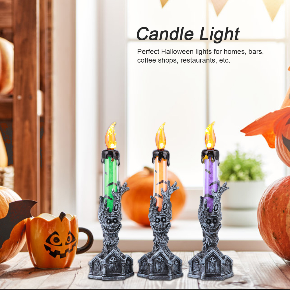 Drei Halloween-Kerzenlichter mit grünen, orangen und lila Röhren. Sie stehen auf einem Tisch mit Kürbissen und einer Jack-o'-Lantern-Tasse.
