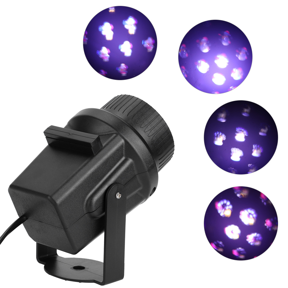 Ein schwarzer Projektor mit Kabel projiziert vier violette, beleuchtete Kreise mit weißen blütenartigen Mustern.