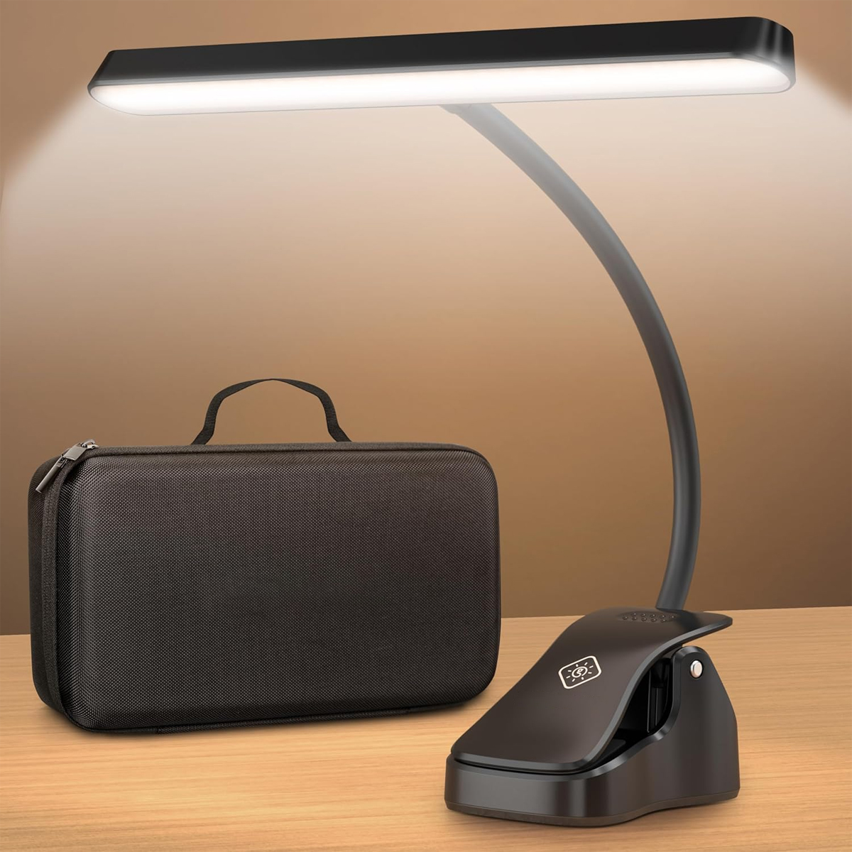 Eine schwarze Klemmleuchte mit hellem LED-Licht, eine schwarze Tasche und eine Holzoberfläche vor braunem Hintergrund.