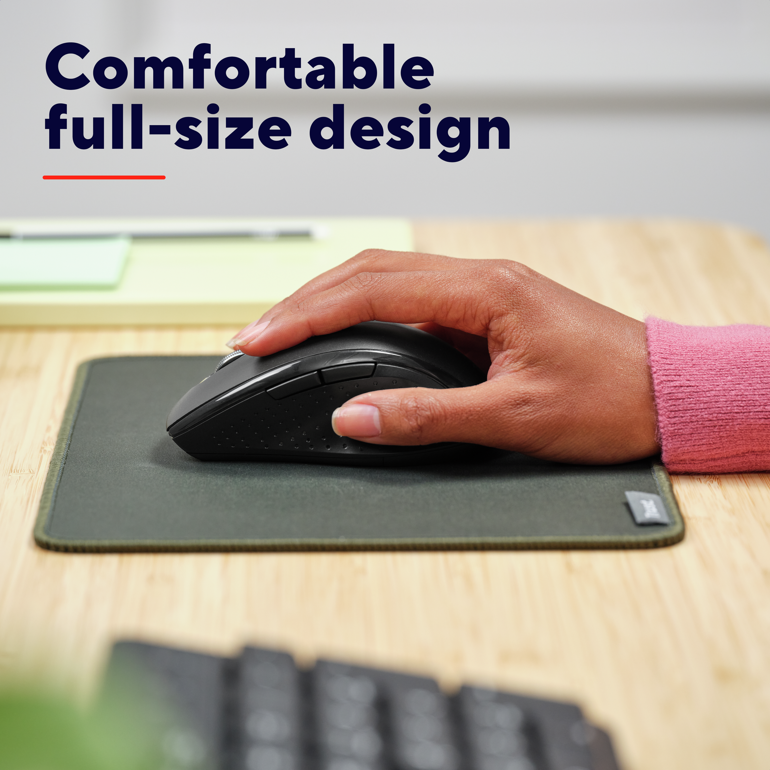 Ręka używa czarnej myszy na zielonej podkładce. Widoczny różowy rękaw. Tekst: Wygodna konstrukcja w pełnym rozmiarze.