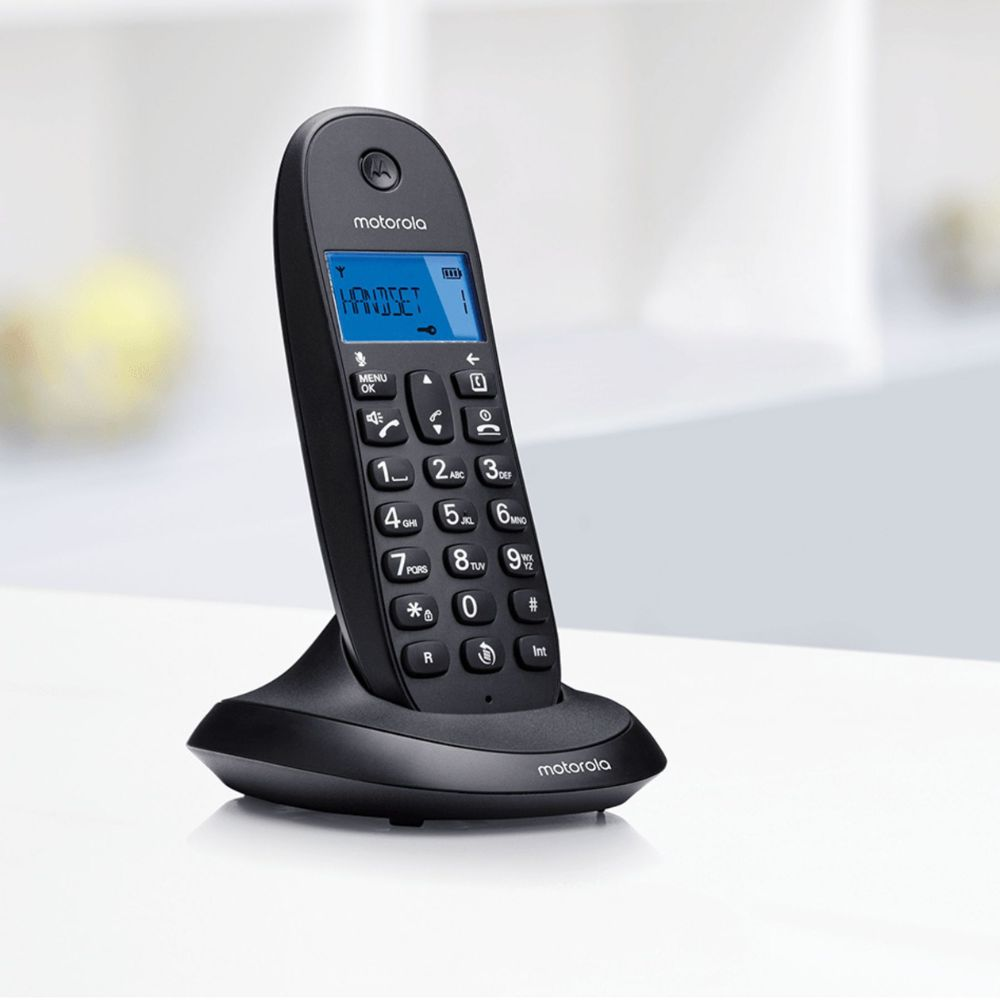 Un telefono cordless Motorola nero su una superficie bianca. Il telefono ha uno schermo blu e pulsanti. Lo sfondo è sfocato.