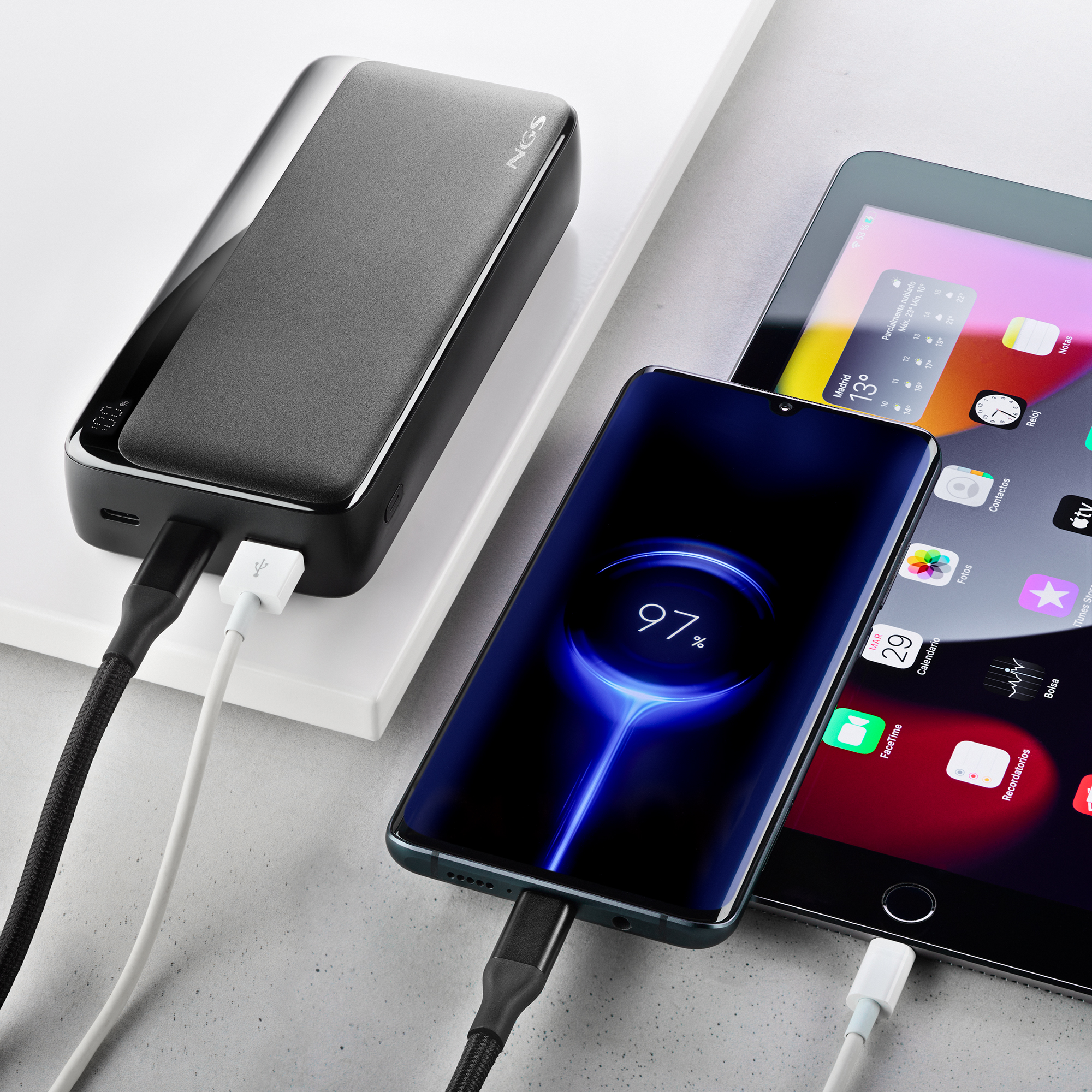 Un teléfono y una tableta se están cargando. Una batería externa está conectada. El teléfono muestra 97% de carga.