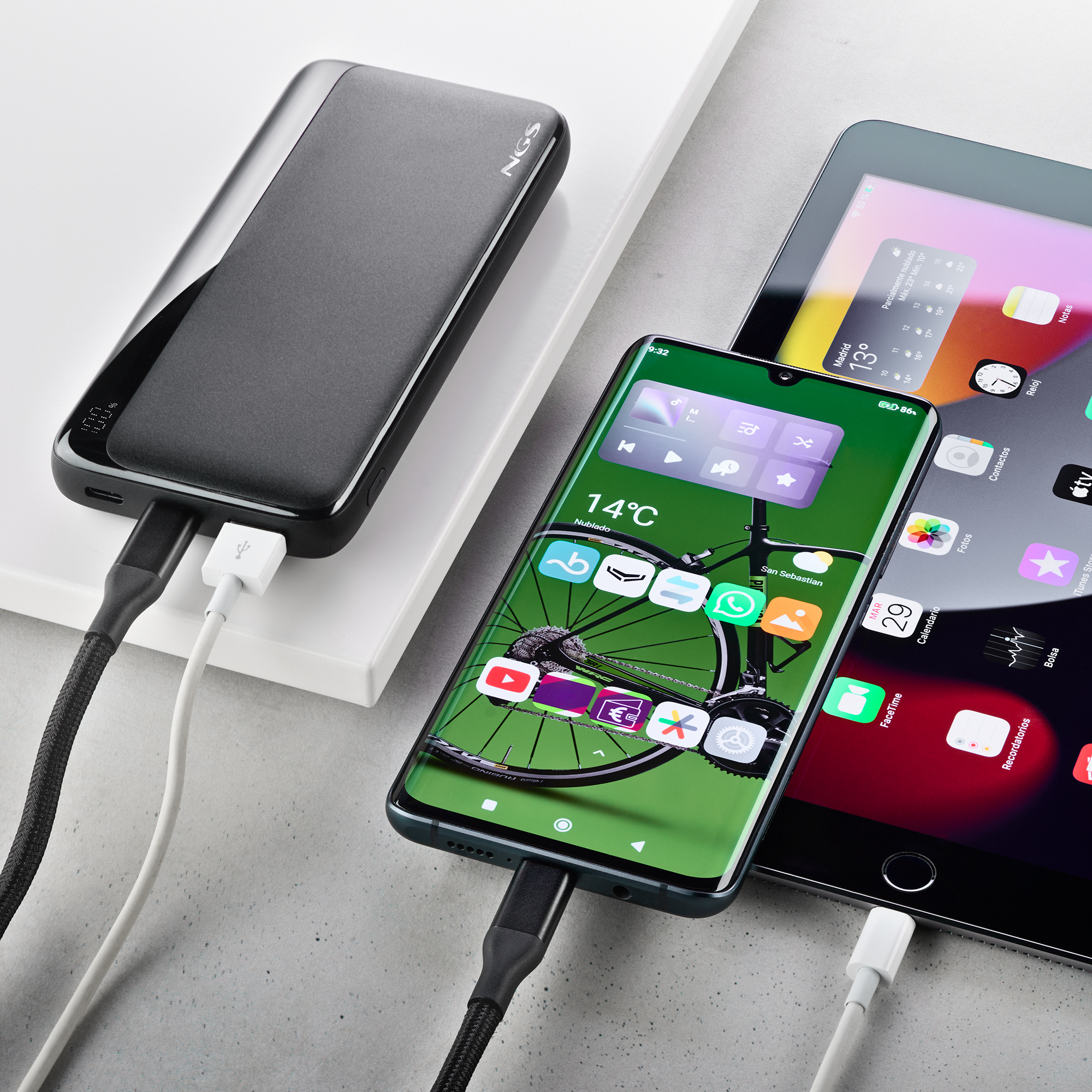 Un teléfono, una tableta y un banco de energía están conectados con cables. El teléfono muestra una rueda de bicicleta.