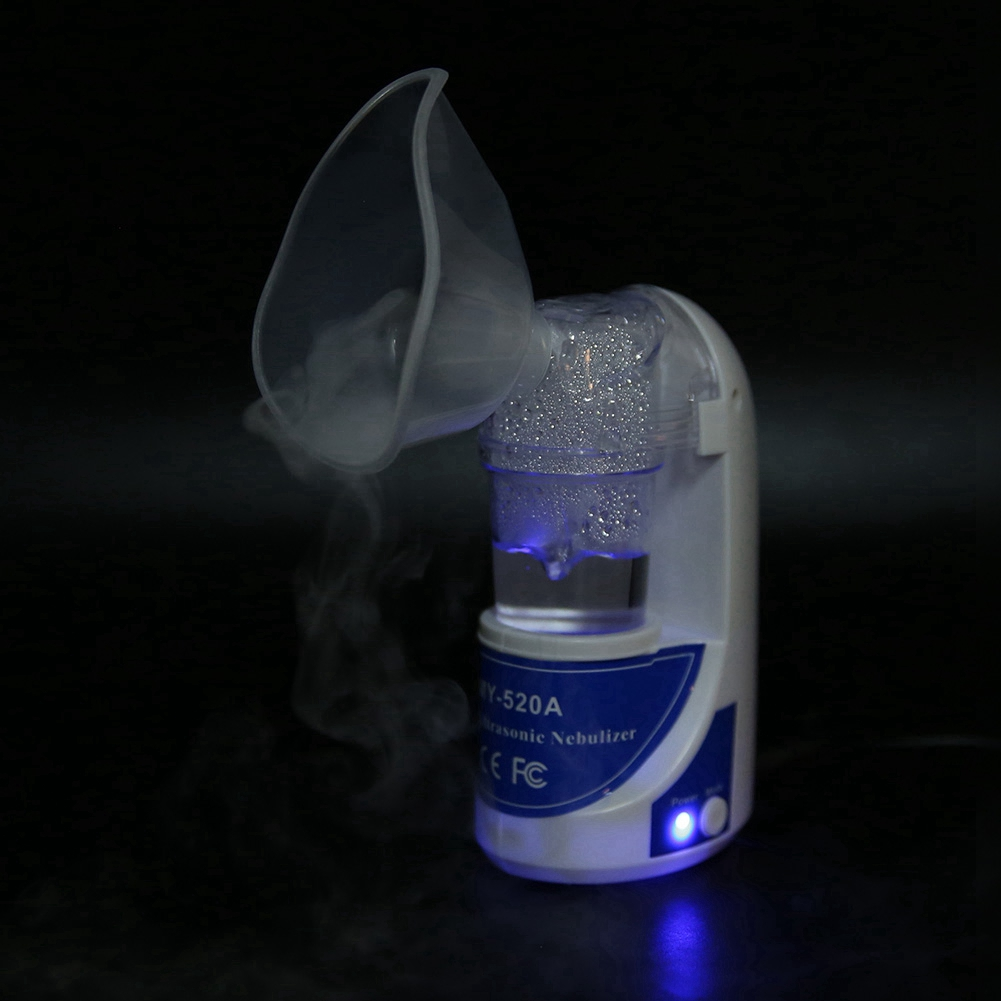 Ein weiß-blauer Ultraschallvernebler mit Dampf, der aus der Maske austritt. Er befindet sich vor einem dunklen Hintergrund, der von blauem Licht beleuchtet wird.