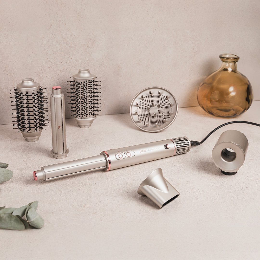 Set per lo styling dei capelli con accessori. Include asciugacapelli, spazzole e diffusore, tutto in argento. Anche un piccolo vaso di vetro.