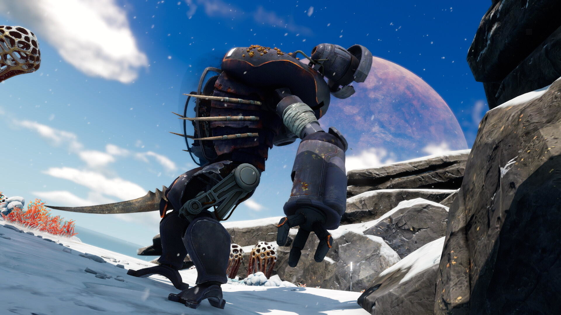 Ciemny robot idzie po zaśnieżonym zboczu. Duża planeta jest w tle. Niebo jest niebieskie z chmurami.