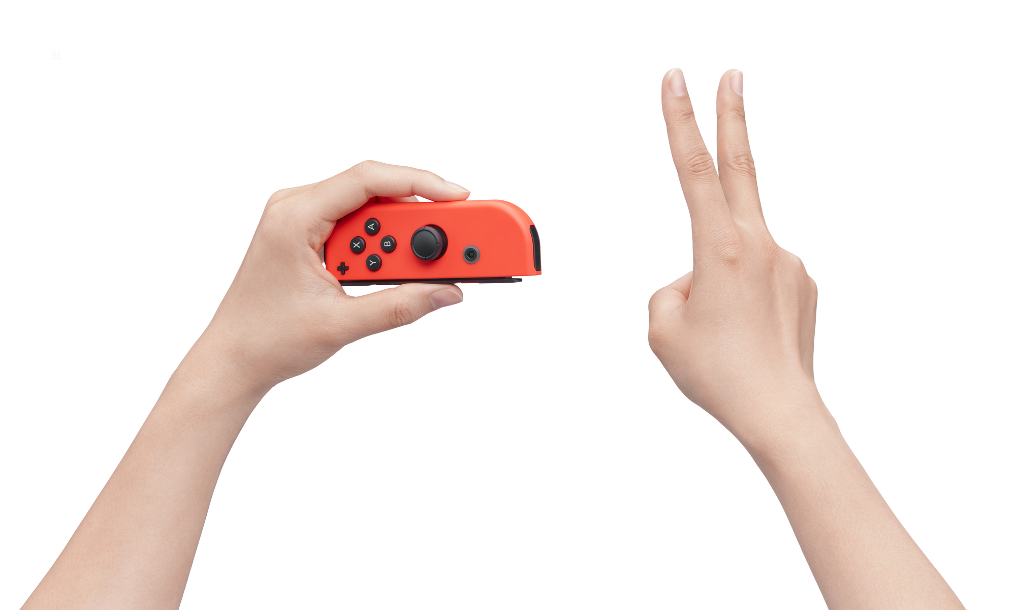 Dłoń trzyma czerwony kontroler Nintendo Switch. Druga dłoń pokazuje znak pokoju. Białe tło.