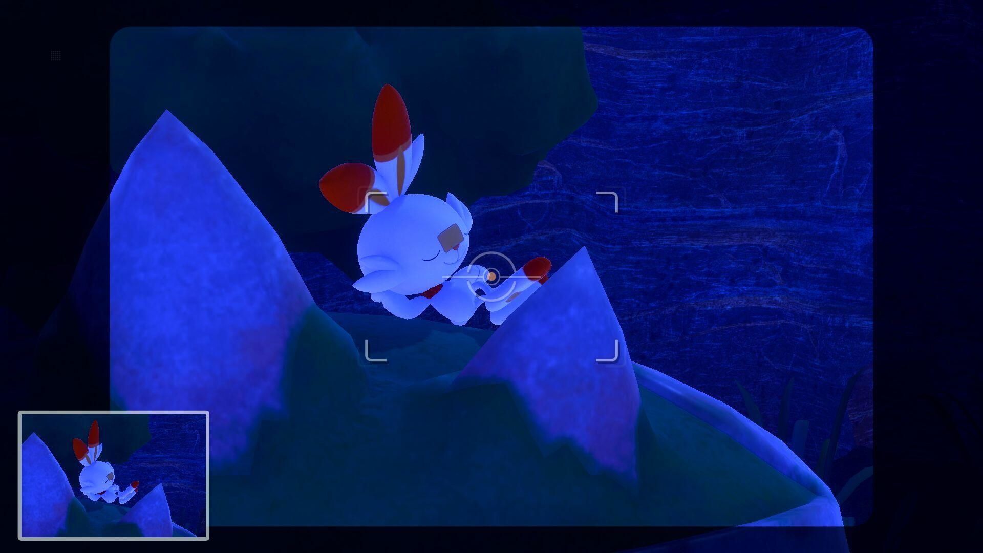 Białe stworzenie z czerwonymi uszami i stopami leży na niebieskiej skale. Tło jest granatowe.