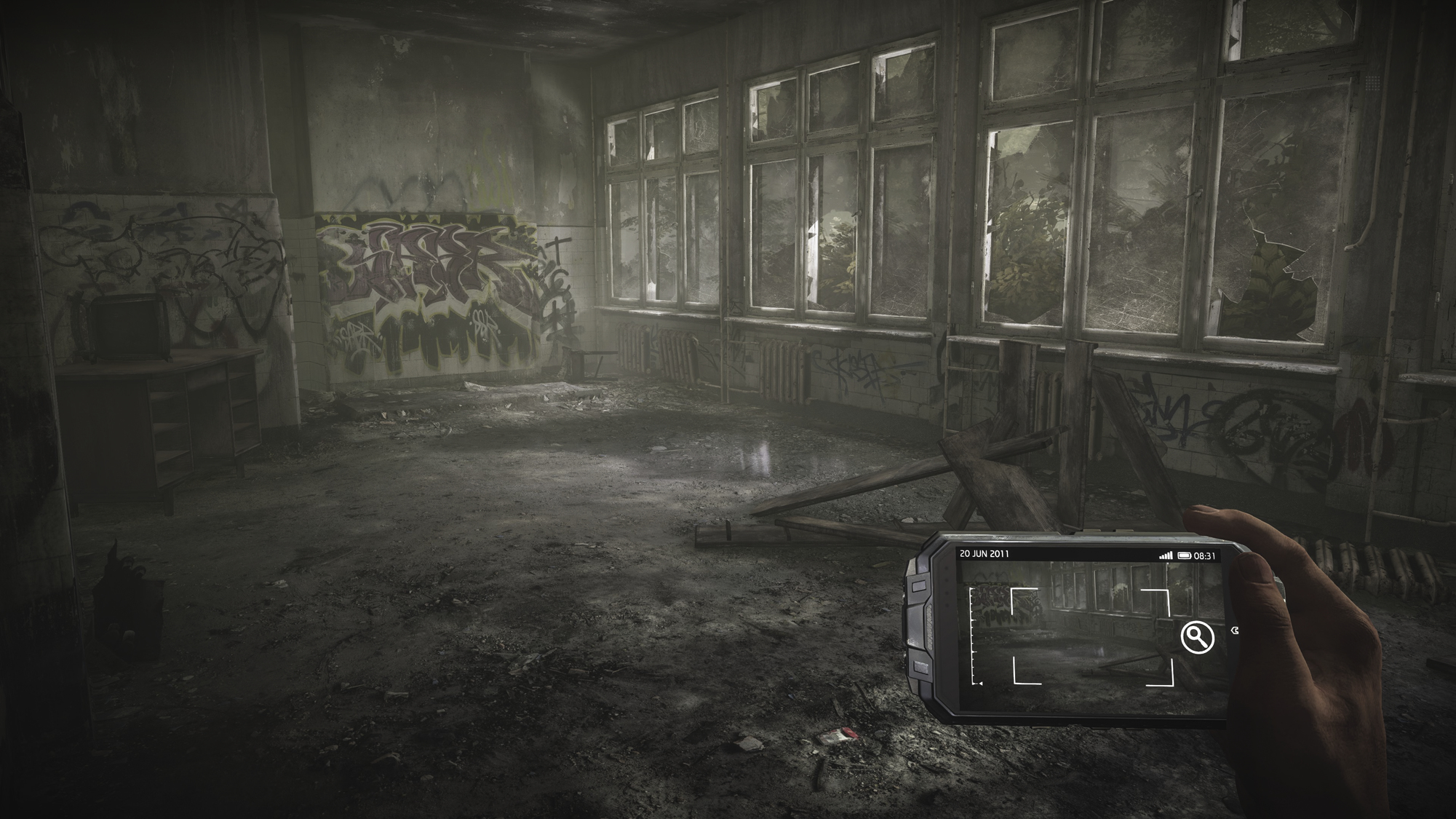 Opuszczony pokój z graffiti, potłuczonymi oknami i dłonią trzymającą urządzenie wyświetlające scenę. Pokój wydaje się zniszczony.