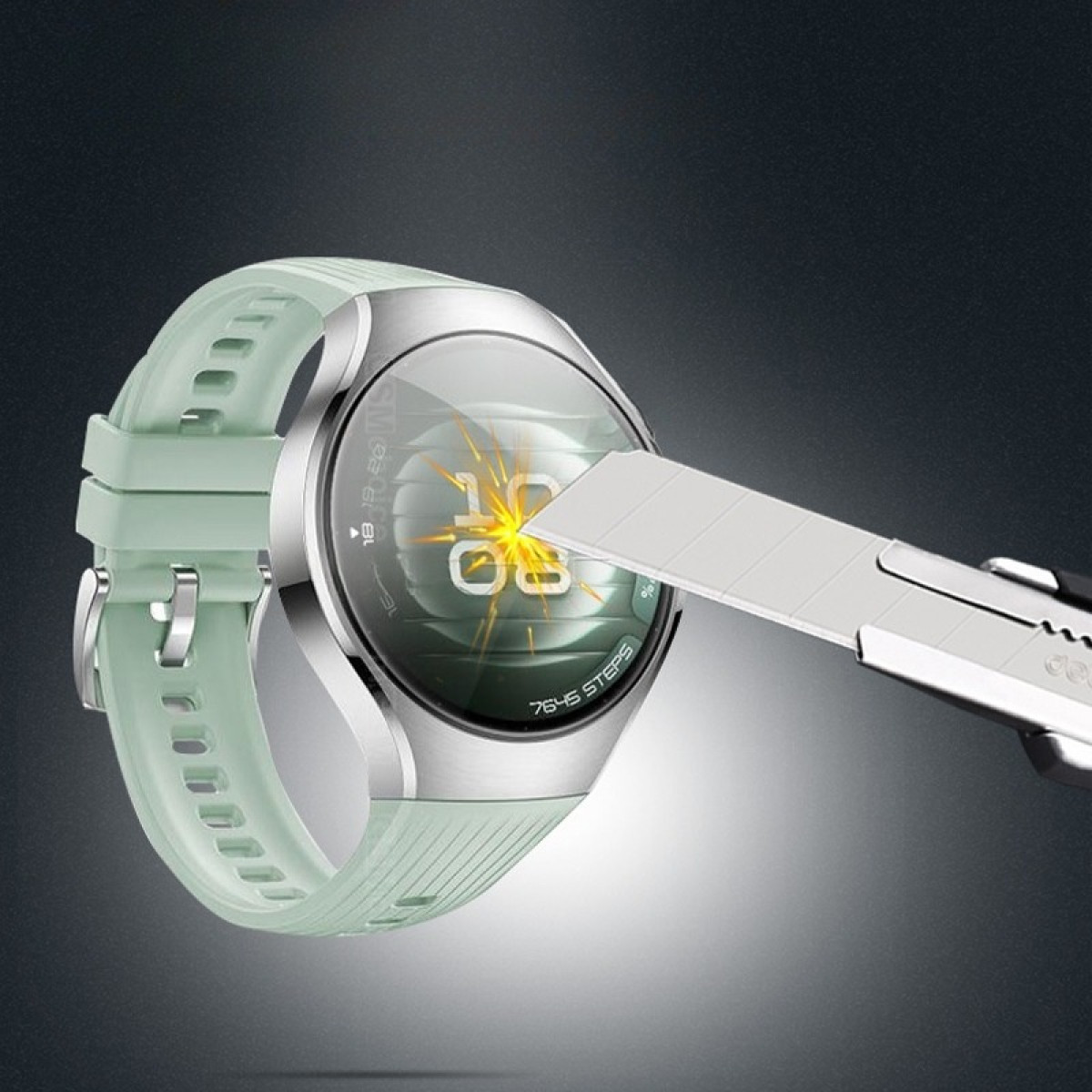 Uno smartwatch verde menta viene testato con un taglierino. L'orologio mostra l'ora e i passi. Lo sfondo è scuro.