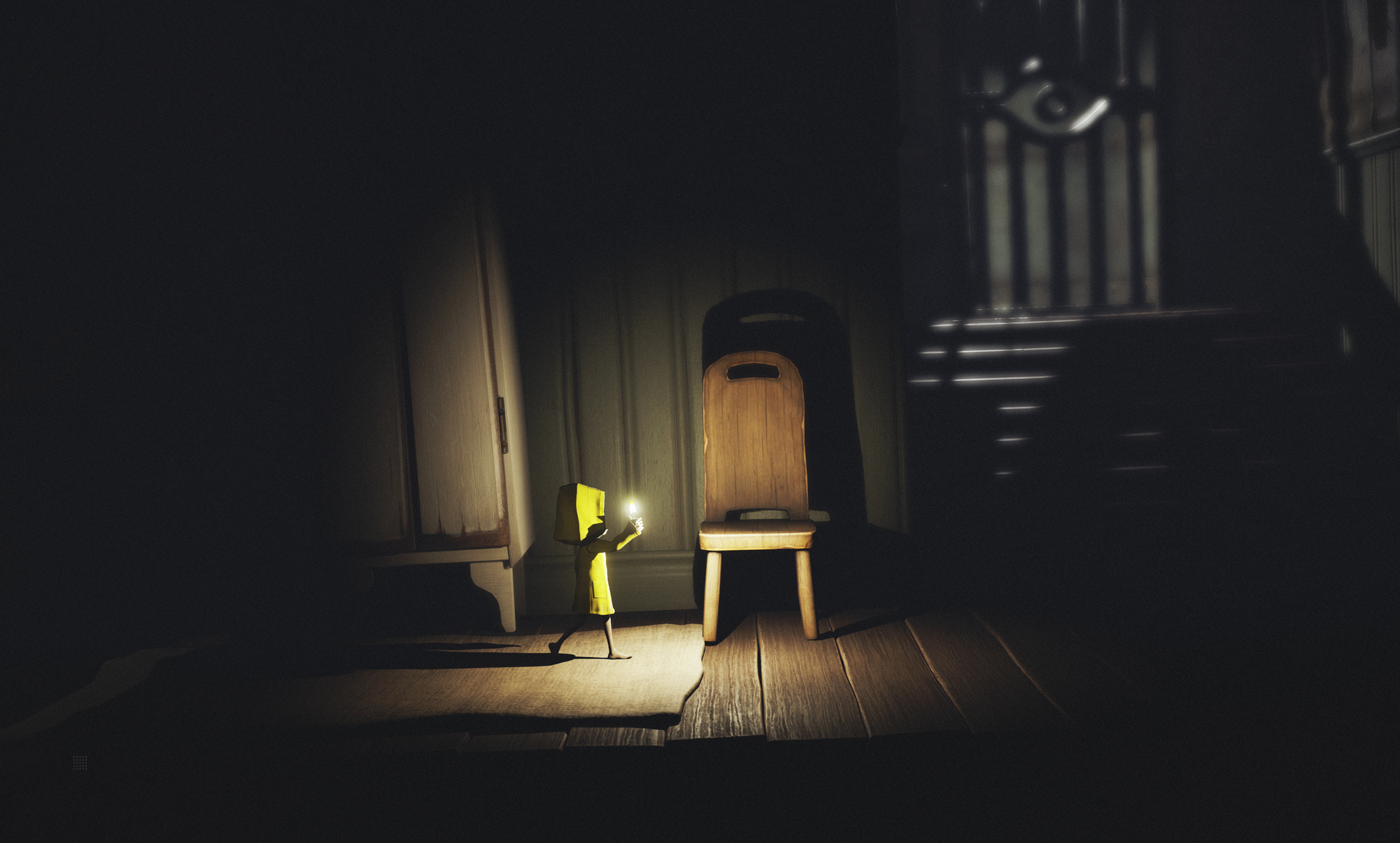 Una figura vestita di giallo tiene una luce in una stanza buia con una sedia e un armadio. Le sbarre sono visibili sullo sfondo.