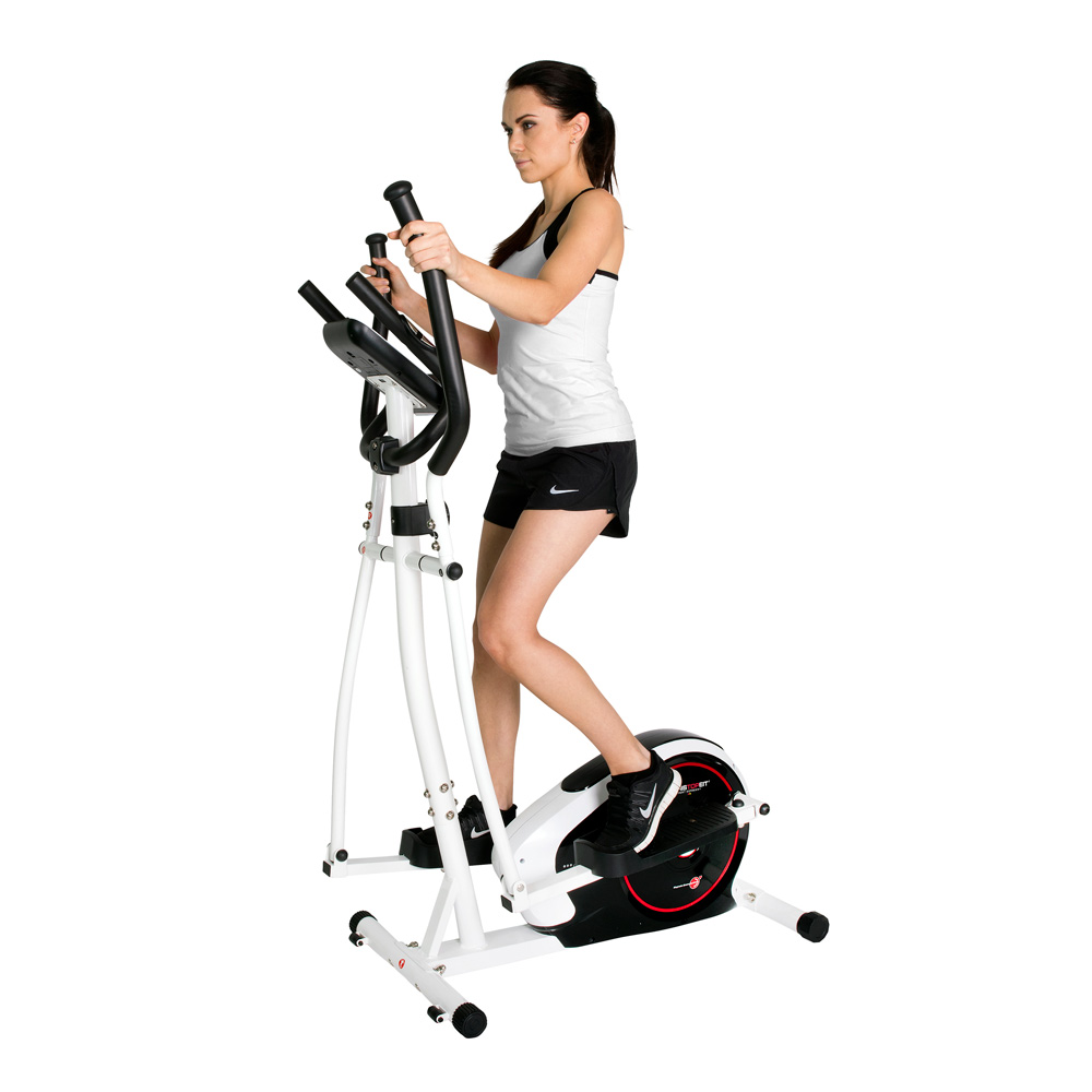 Eine Frau trainiert auf einem weißen Crosstrainer. Sie trägt schwarze Shorts, ein weißes Oberteil und schwarze Turnschuhe. Die Maschine hat schwarze Griffe.