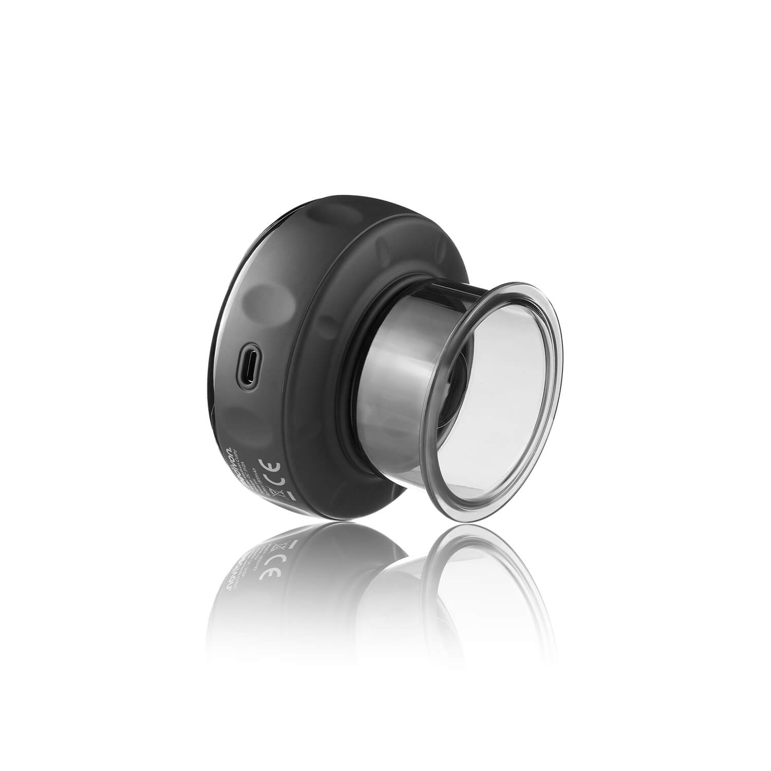 Un dispositivo negro con un accesorio claro y circular. El dispositivo está sobre una superficie blanca con su reflejo visible.