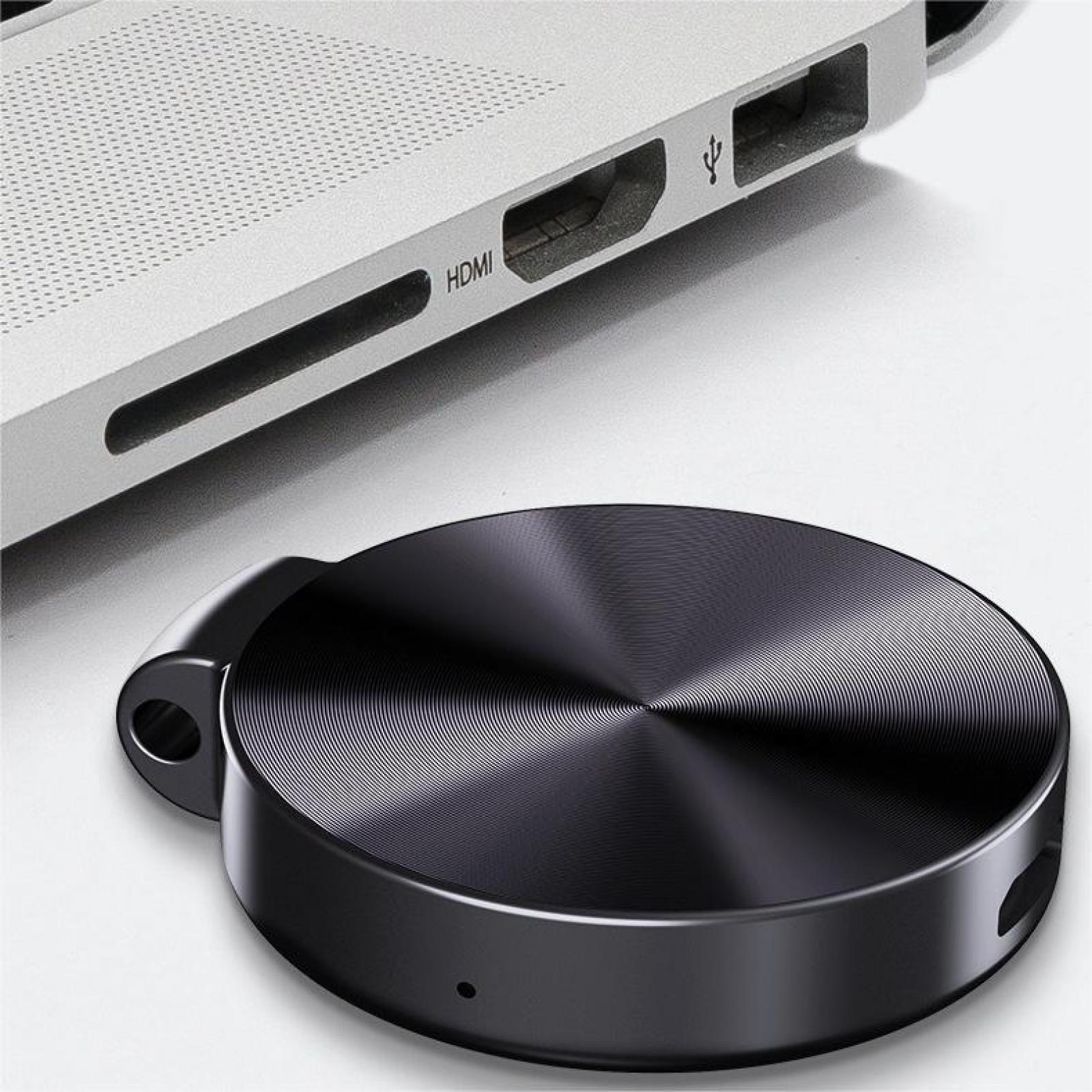 Ein schwarzes, kreisförmiges Gerät neben einem Laptop. Der Laptop hat HDMI- und andere Anschlüsse.