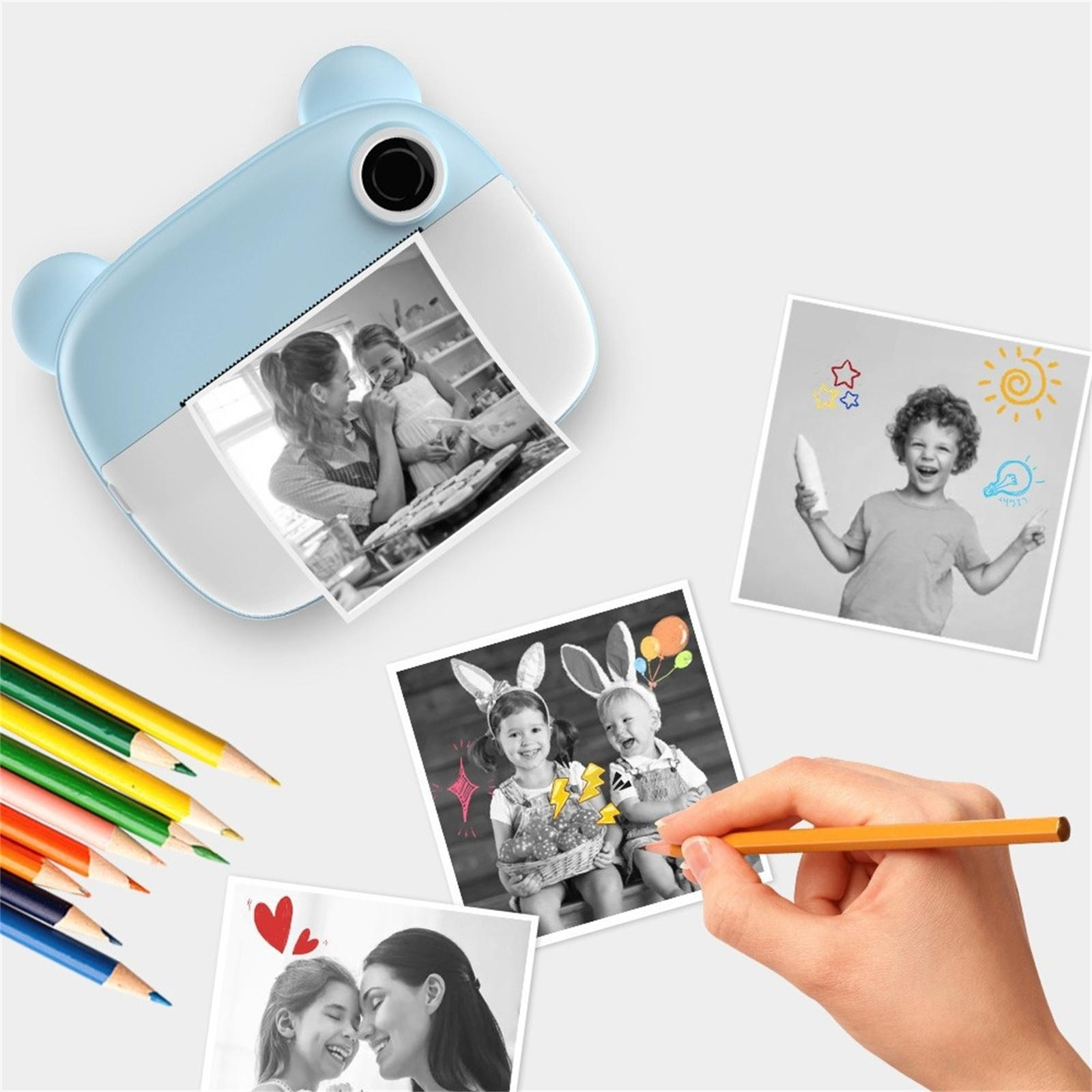 Ein blauer, bärenförmiger Fotodrucker mit Fotos und Buntstiften. Hand zeichnet mit Bleistift auf einem Foto.