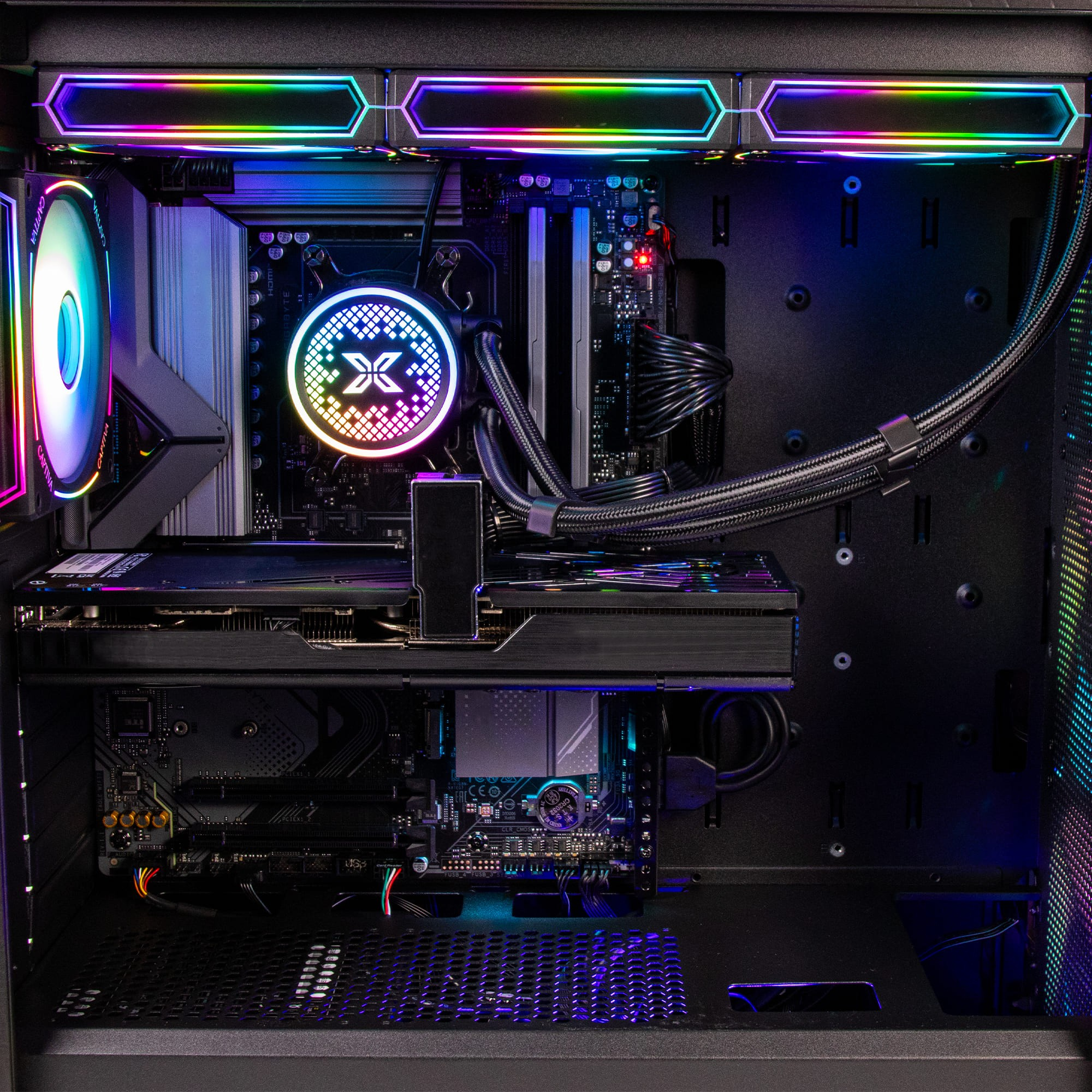 Dentro de una carcasa de computadora, son visibles componentes, incluyendo una placa base, una tarjeta gráfica y un enfriador líquido, todos iluminados por iluminación RGB.