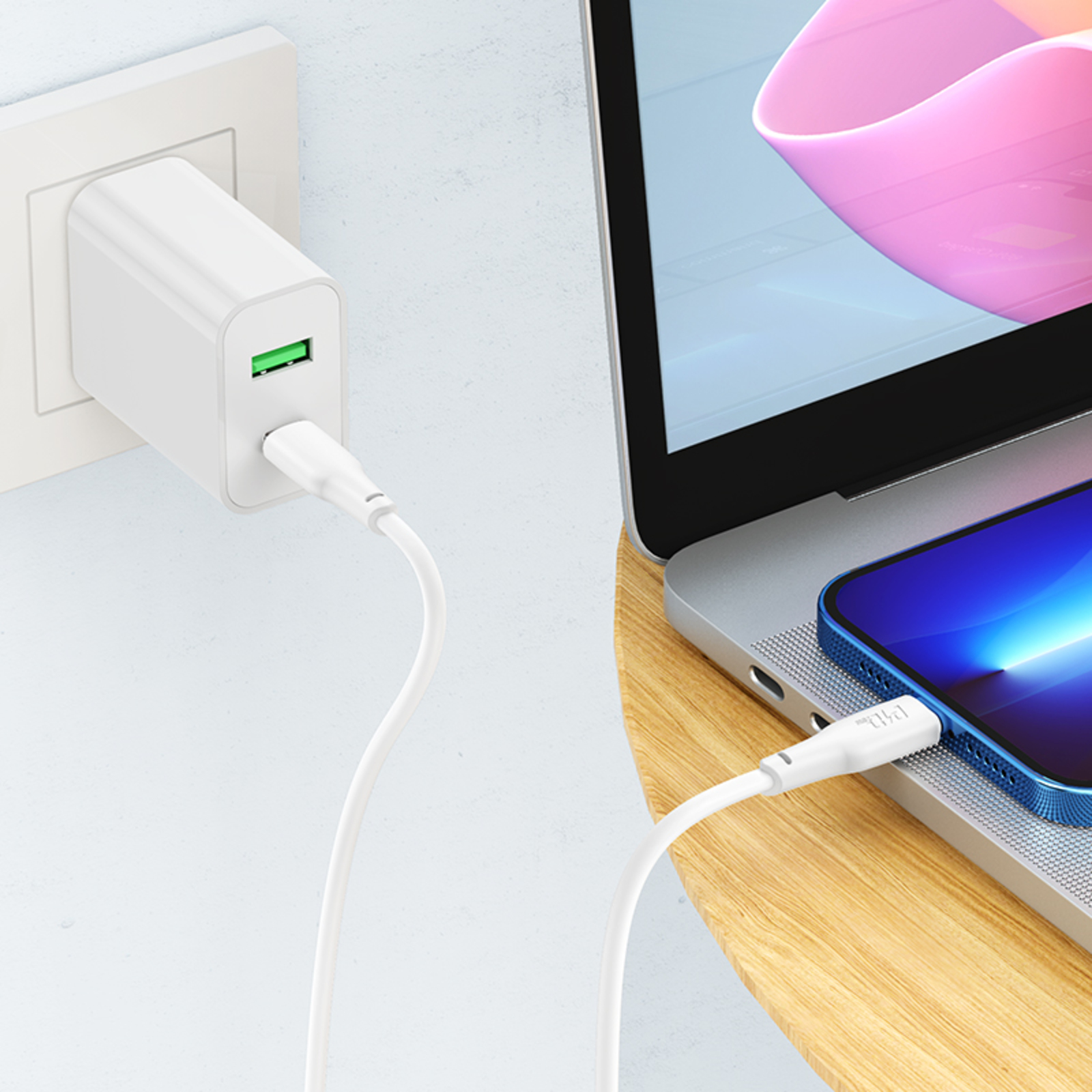 Weißes Ladegerät an einer Steckdose, verbunden mit einem Laptop und einem blauen Smartphone mit weißem Kabel.