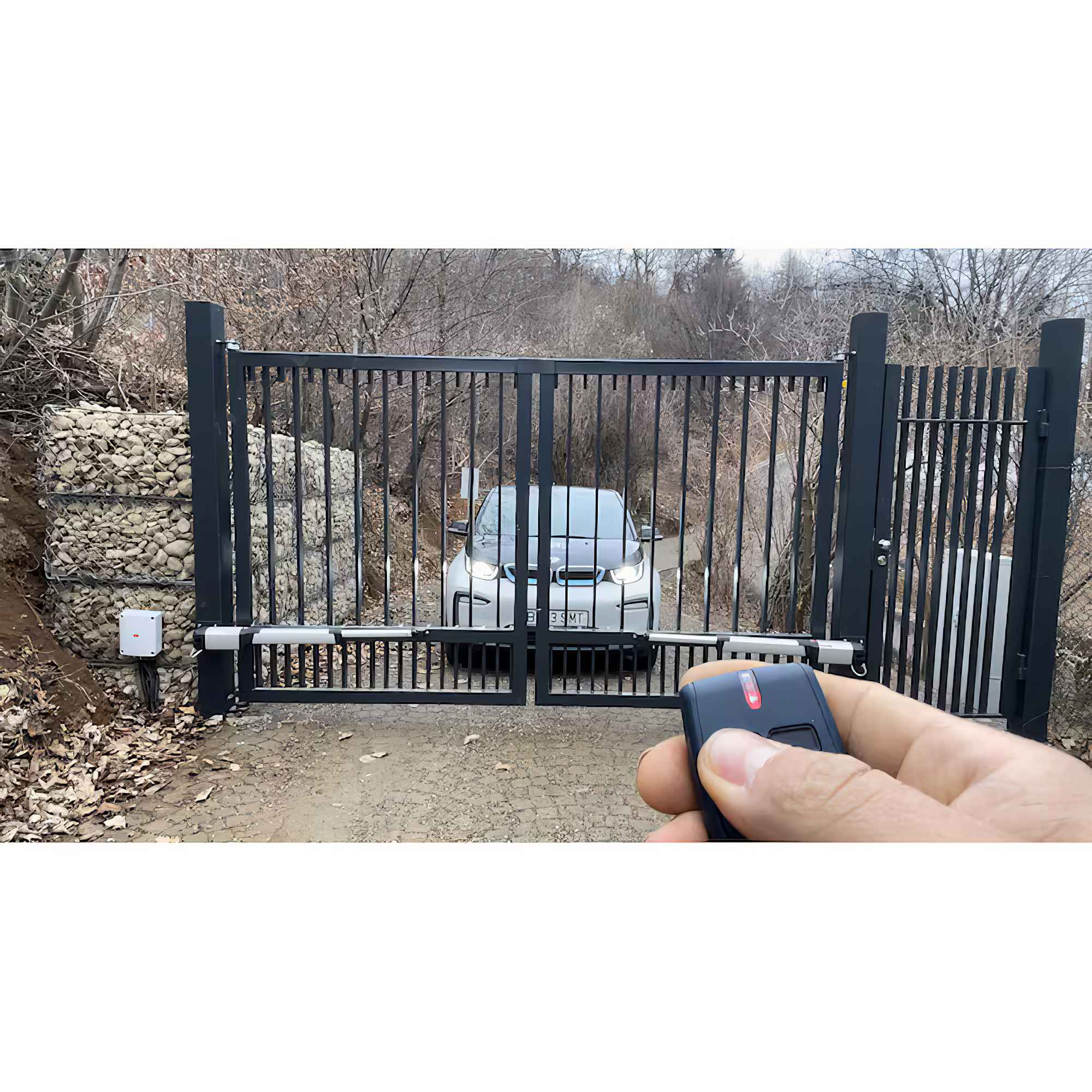 Ein Auto hinter einem schwarzen Tor wird mit einer Fernbedienung gesteuert. Das Auto ist weiß und im Hintergrund sind Bäume.