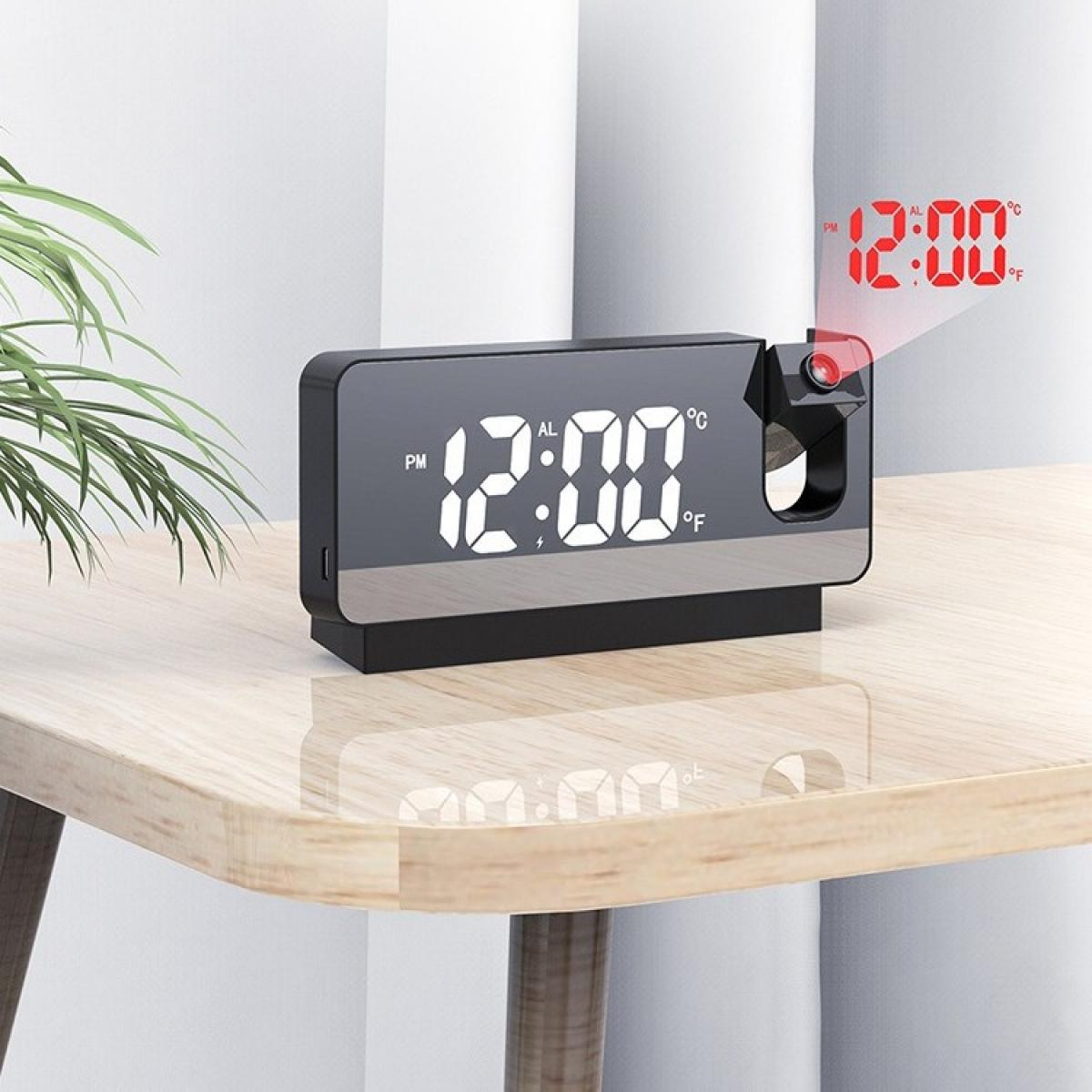 Eine Digitaluhr mit 12:00 PM projiziert die Uhrzeit an die Wand. Sie steht auf einem Holztisch, im Hintergrund eine grüne Pflanze.