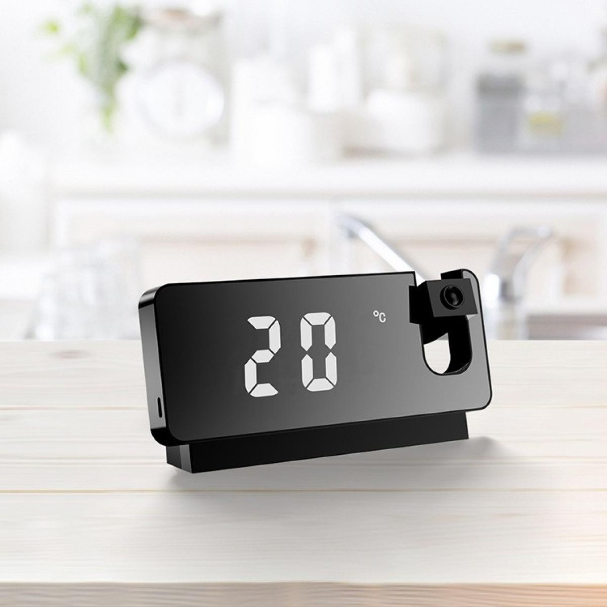 Eine schwarze Digitaluhr zeigt 20 Grad Celsius an. Sie steht auf einer Holzoberfläche mit verschwommenem Küchenhintergrund.