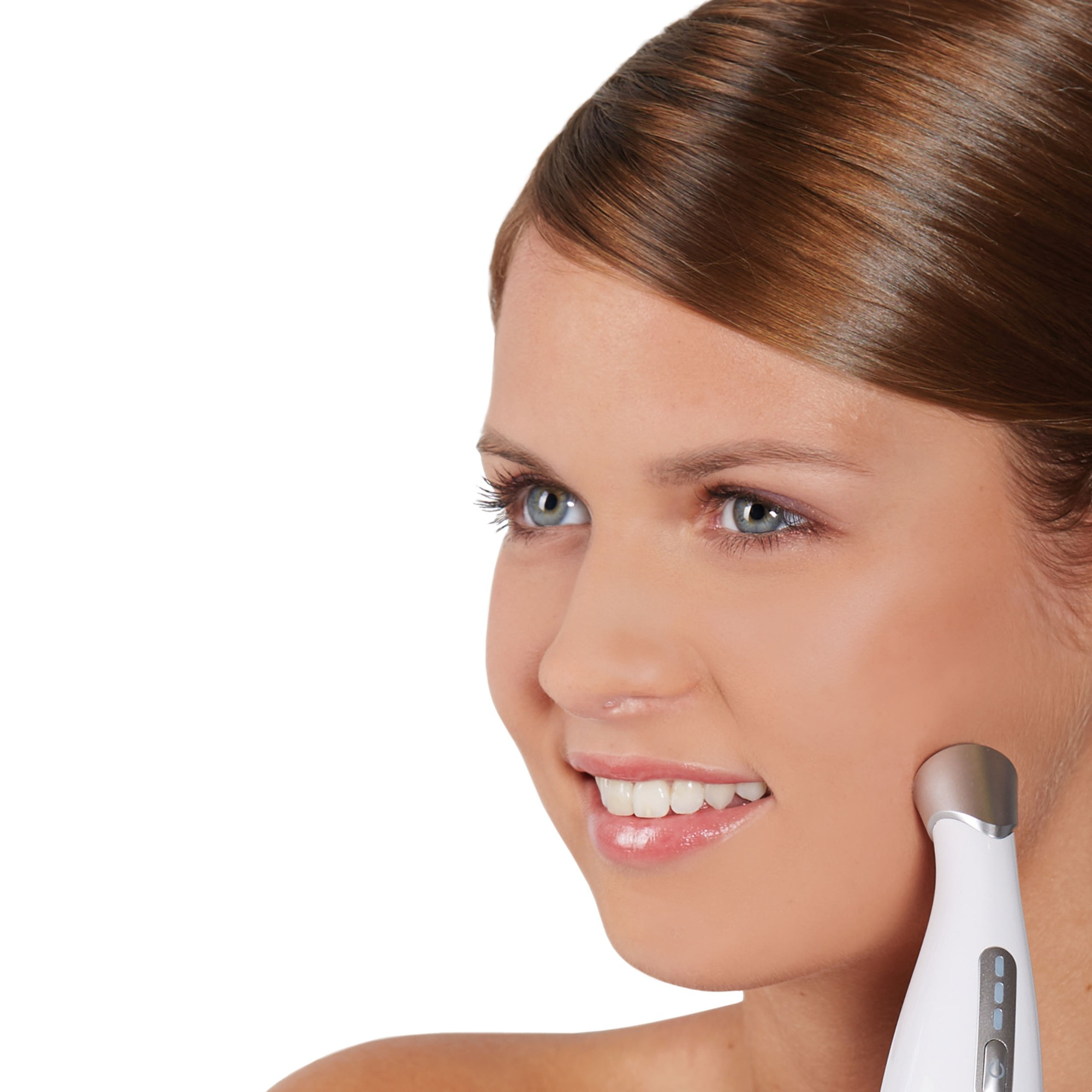 A woman smiles while using a white beauty device on her cheek. She has light skin and brown hair. White background.