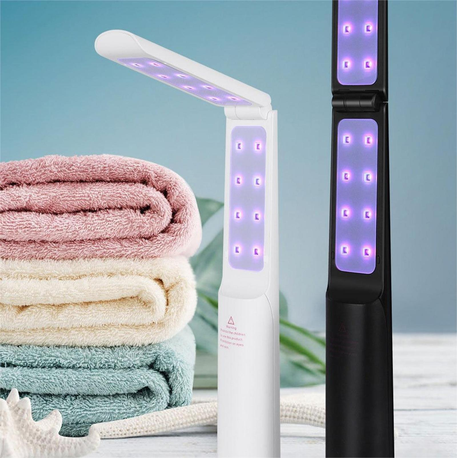 Das Bild zeigt eine weiße und eine schwarze UV-Lampe mit einem Stapel Handtücher in Rosa, Creme und Türkis. Ein Seestern ist im Vordergrund.