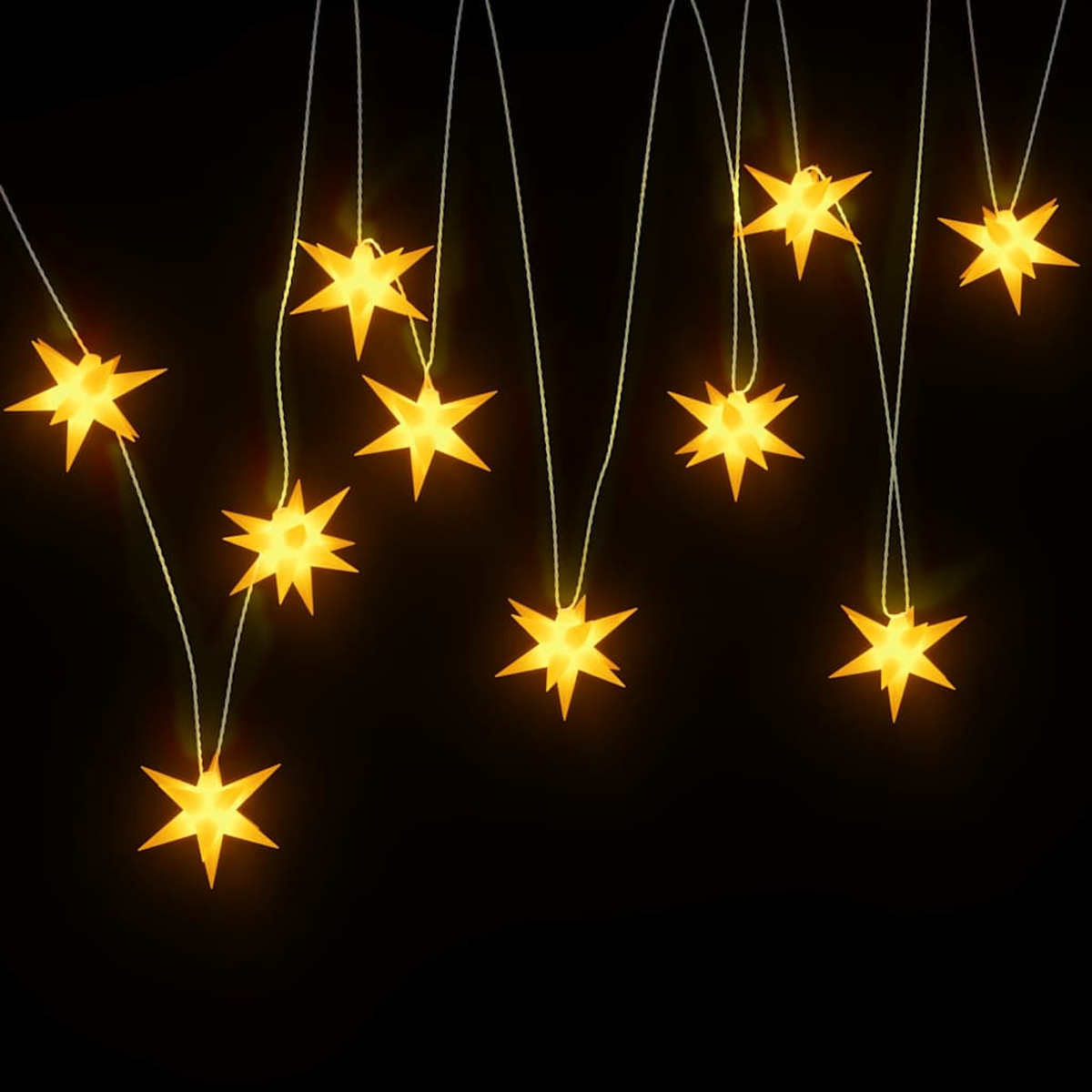 Leuchtende gelbe sternförmige Lichter hängen vor einem schwarzen Hintergrund. Jeder Stern ist an einem dünnen weißen Faden aufgehängt.
