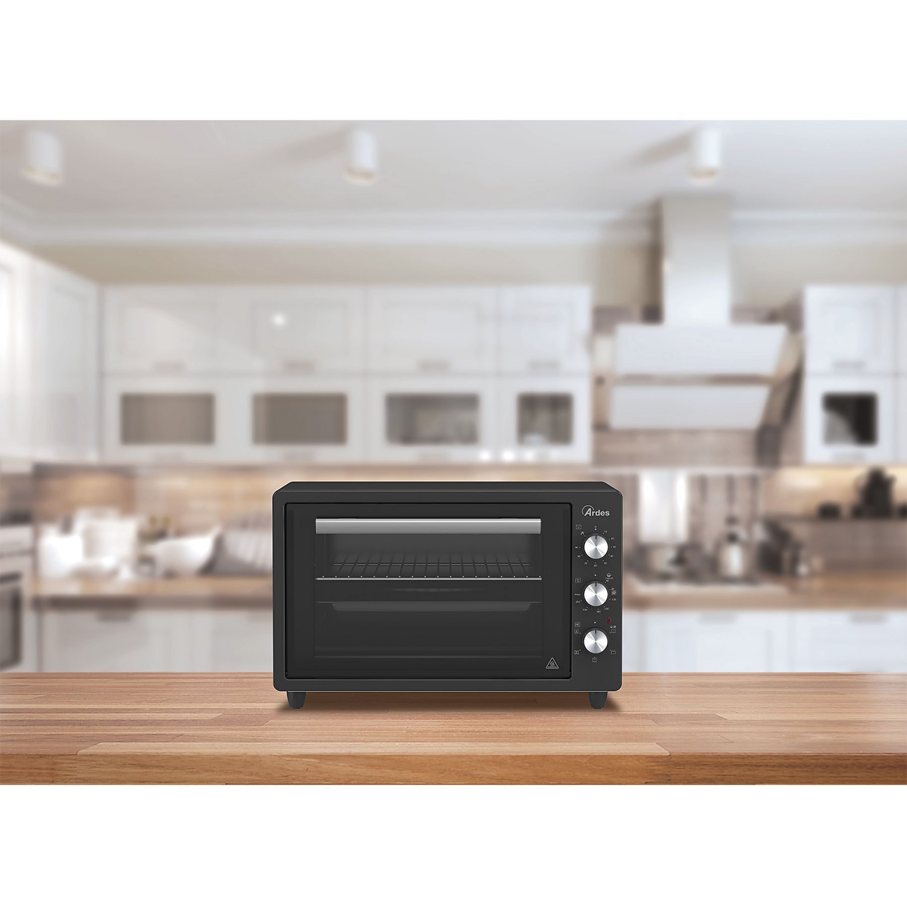 Czarny piekarnik na drewnianym stole w kuchni. Pokrętła po prawej stronie. Białe szafki w tle.