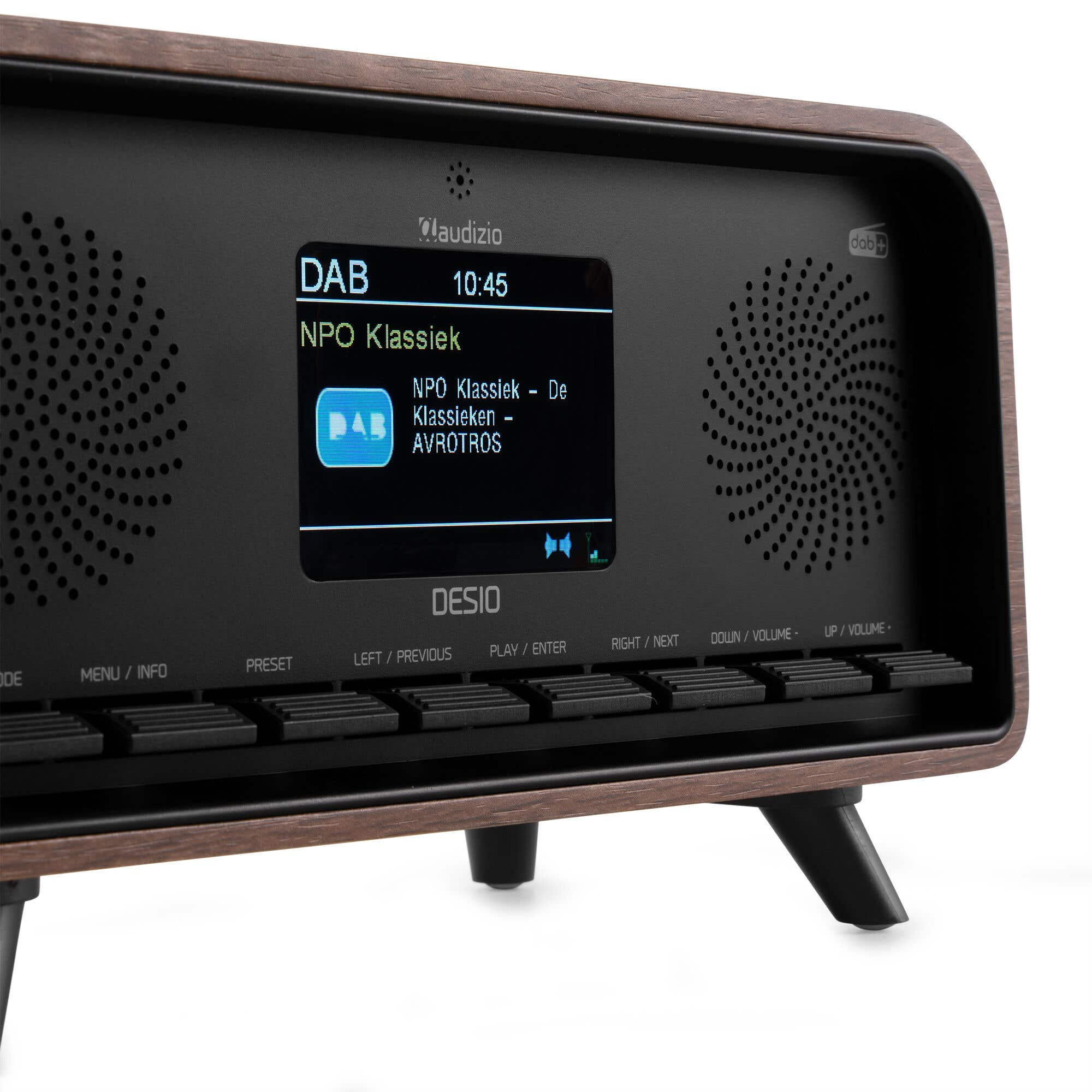 Ein DAB-Radio zeigt 'NPO Klassiek' an. Es hat einen Holzrahmen, Lautsprecher und Tasten zur Steuerung. Es steht auf Weiß.