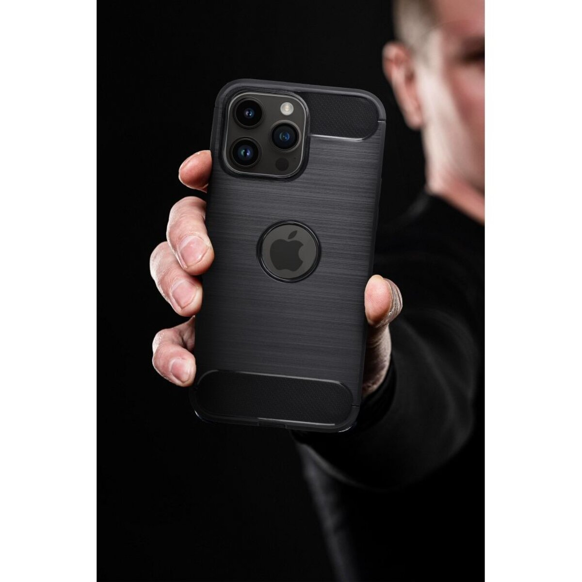 Eine Hand hält ein schwarzes iPhone mit Hülle. Das Telefon hat drei Kameras und ein Apple-Logo. Der Hintergrund ist dunkel.