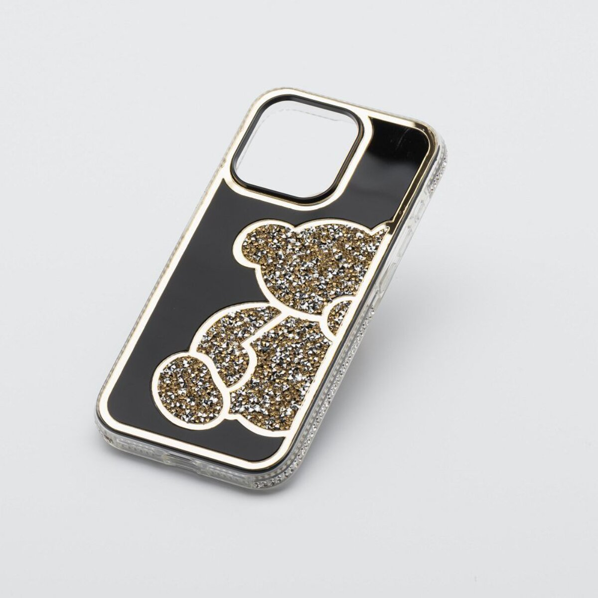 Eine Handyhülle mit schwarzem Hintergrund und einem glitzernden goldenen Teddybären-Design. Die Hülle hat einen transparenten Rand und einen Kameraausschnitt.