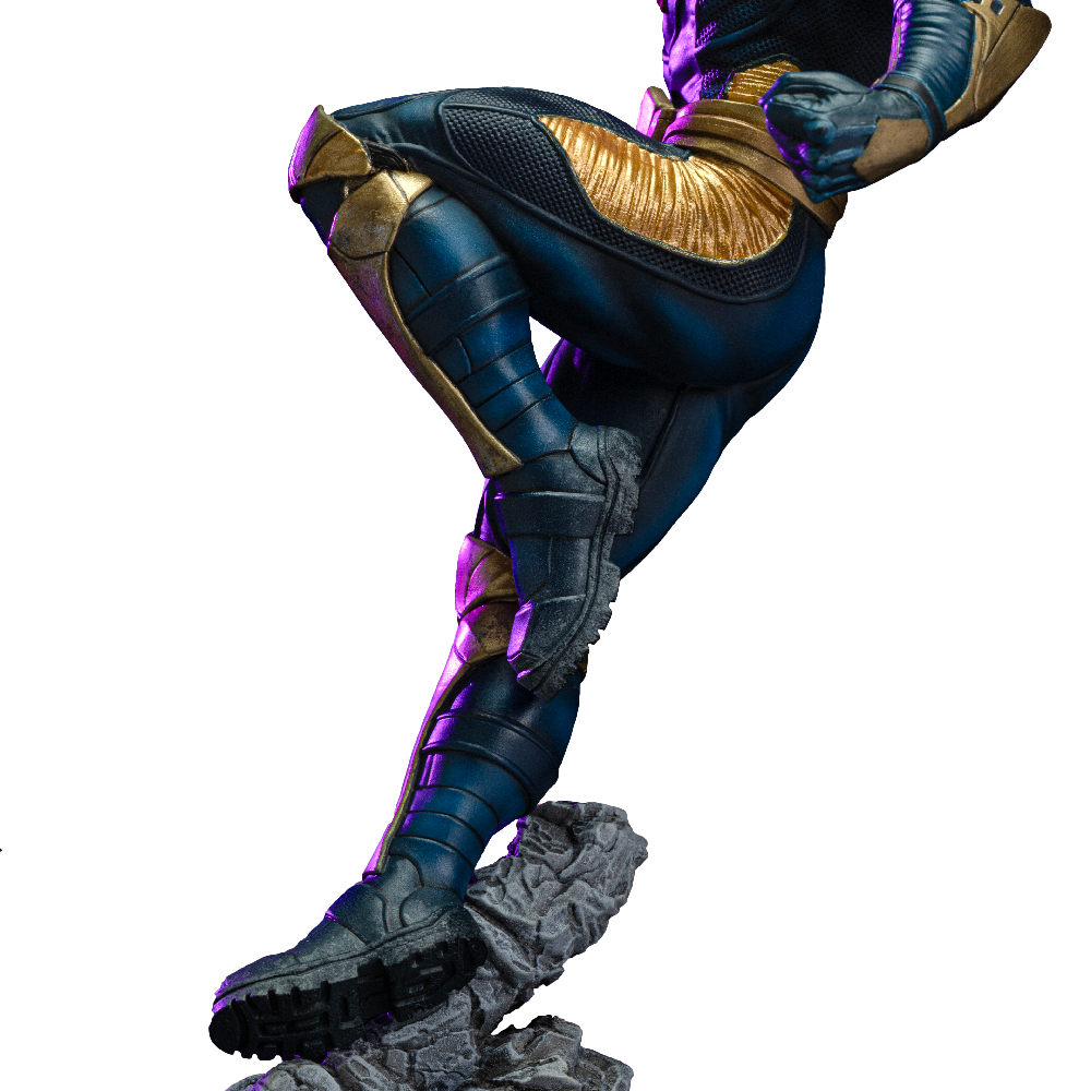 Una figura in tuta blu e oro è catturata a metà salto. La figura è su una roccia grigia, gli stivali sono neri. Lo sfondo è bianco.