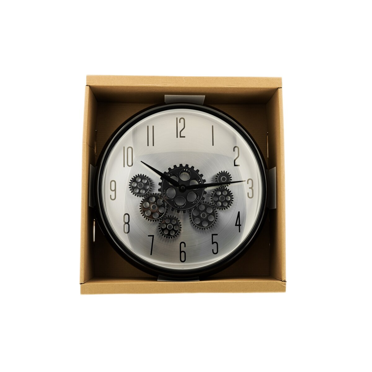 Eine Uhr mit sichtbaren Zahnrädern in einem Karton. Die Uhr hat schwarze Zeiger und ein silbernes Zifferblatt mit Zahlen.