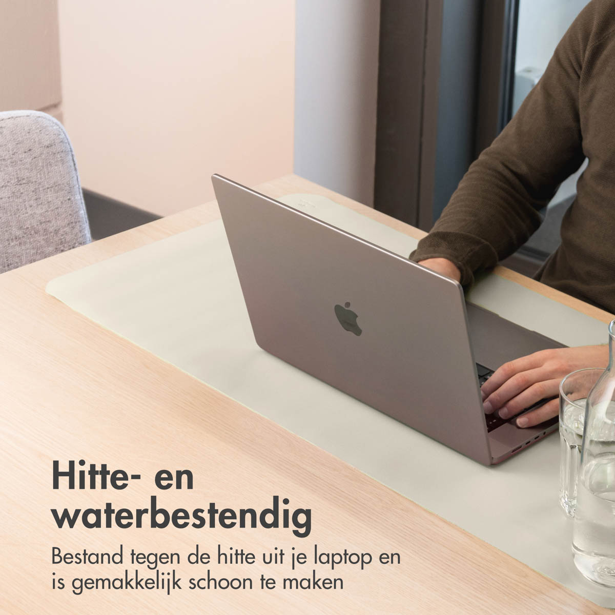 Una persona usa un laptop su una scrivania. Accanto c'è una bottiglia d'acqua e un bicchiere. Il testo dice resistente al calore e all'acqua.
