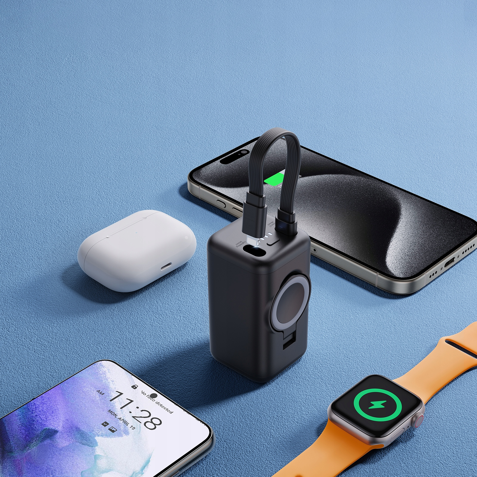 Batterie externe noire chargeant un téléphone. Autres appareils : AirPods, montre connectée et autre téléphone sur une surface bleue.