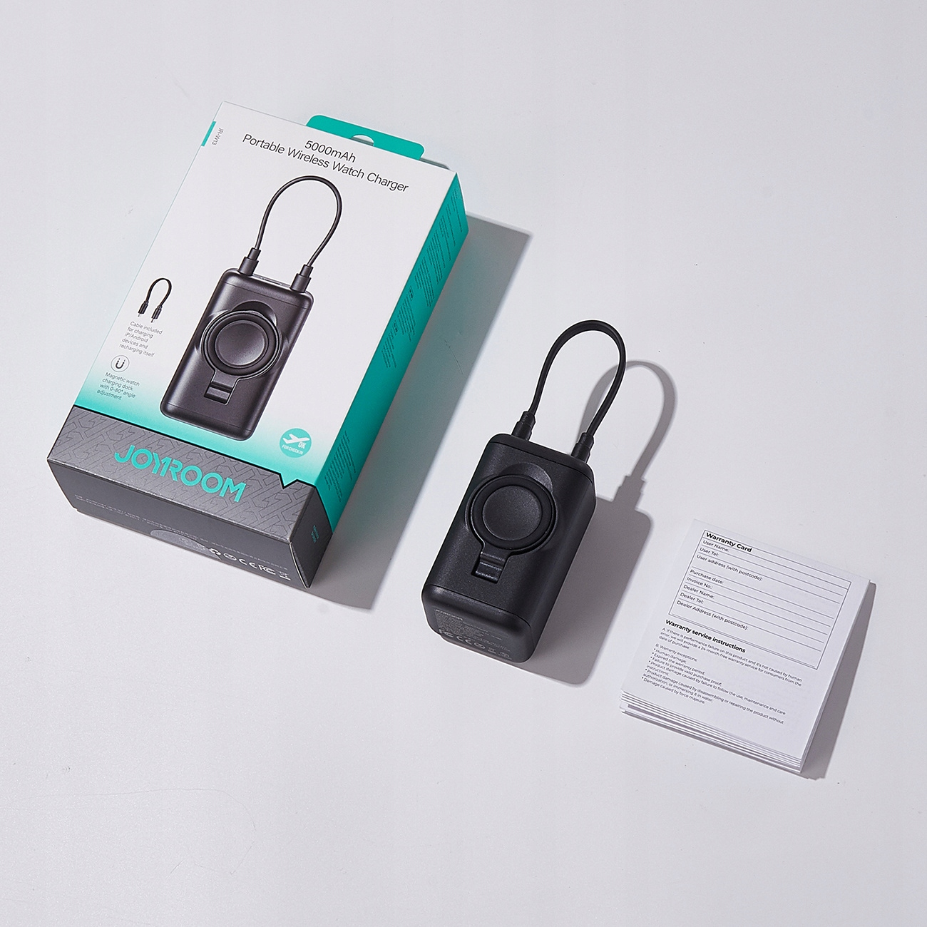 Un chargeur de montre sans fil noir avec une boîte et une carte de garantie sur une surface blanche.