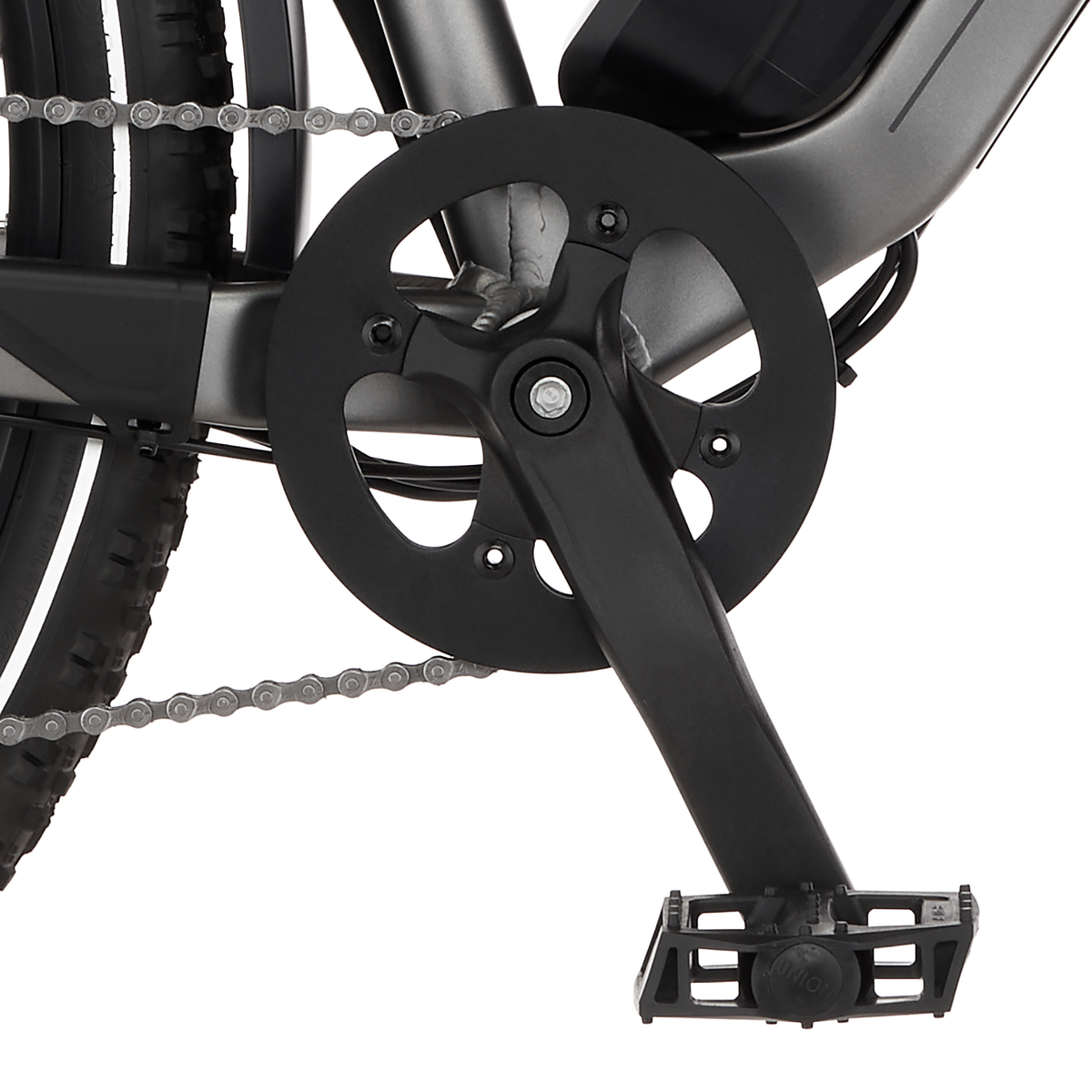 Nahaufnahme von schwarzem Fahrradkurbelsatz, Pedalen und Kette. Der Fahrradrahmen ist grau. Reifen sind schwarz mit weißen Akzenten.