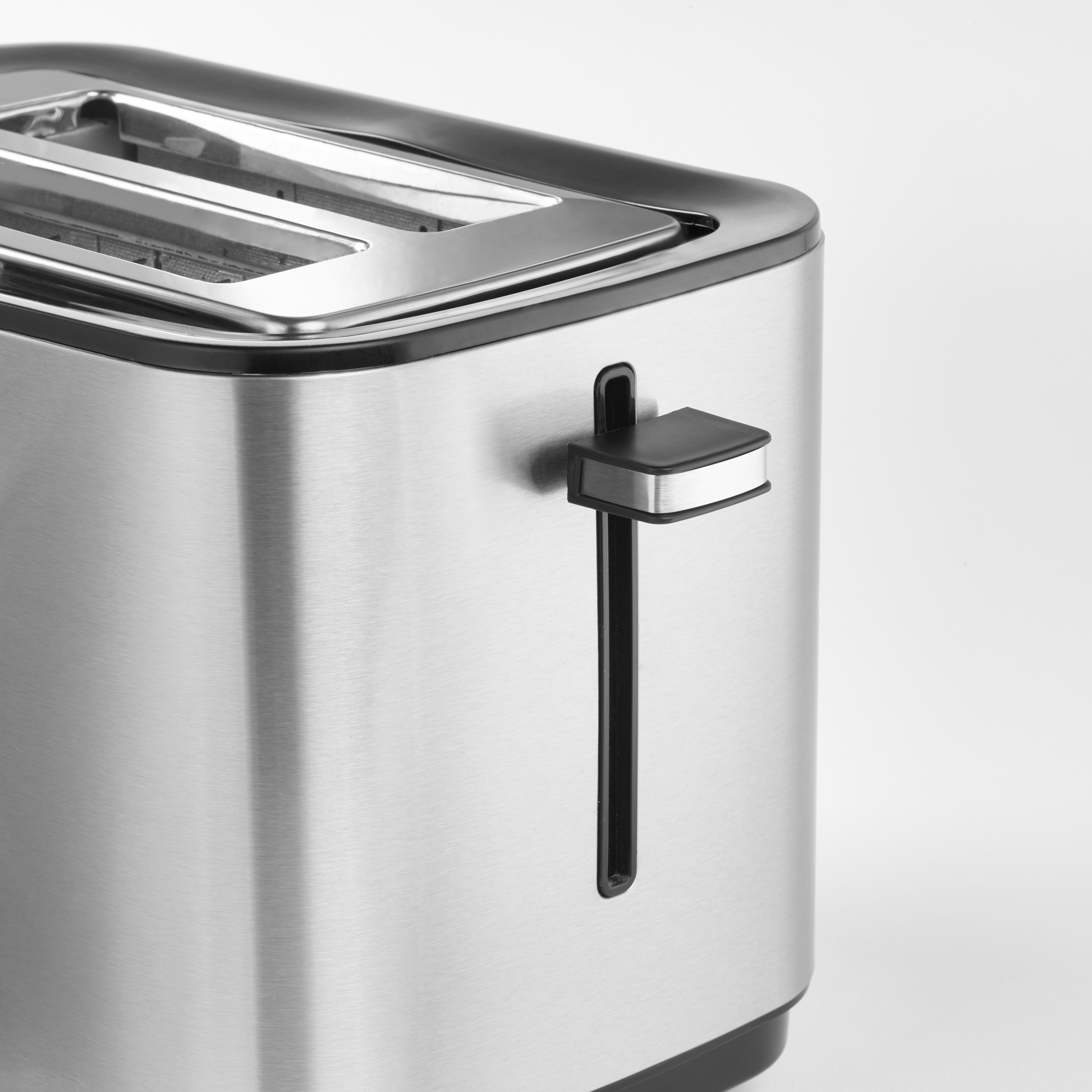 Nahaufnahme eines Toasters aus Edelstahl. Er hat einen schwarzen Hebel und einen schwarzen Deckel. Der Hintergrund ist weiß.