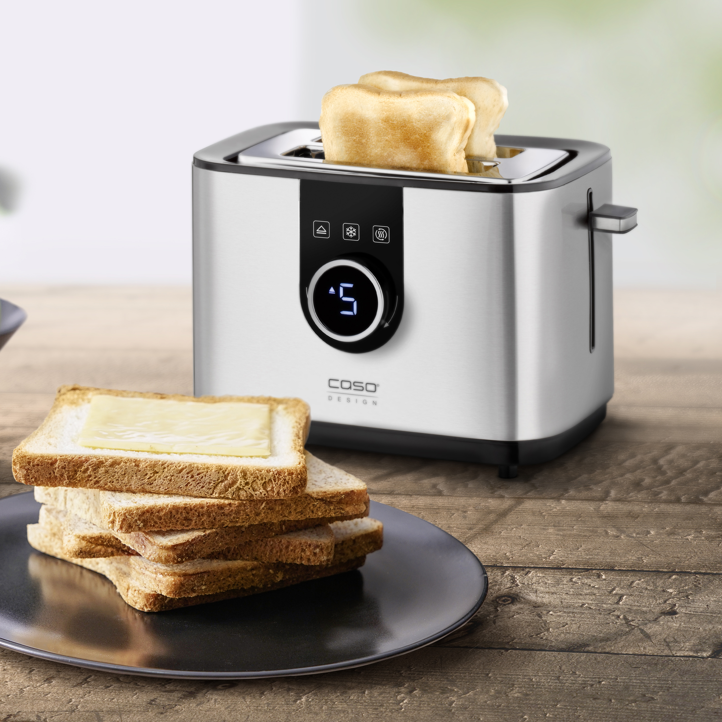 Ein Toaster mit zwei herausspringenden Toastscheiben. Toastscheiben mit Käse auf einem Teller.