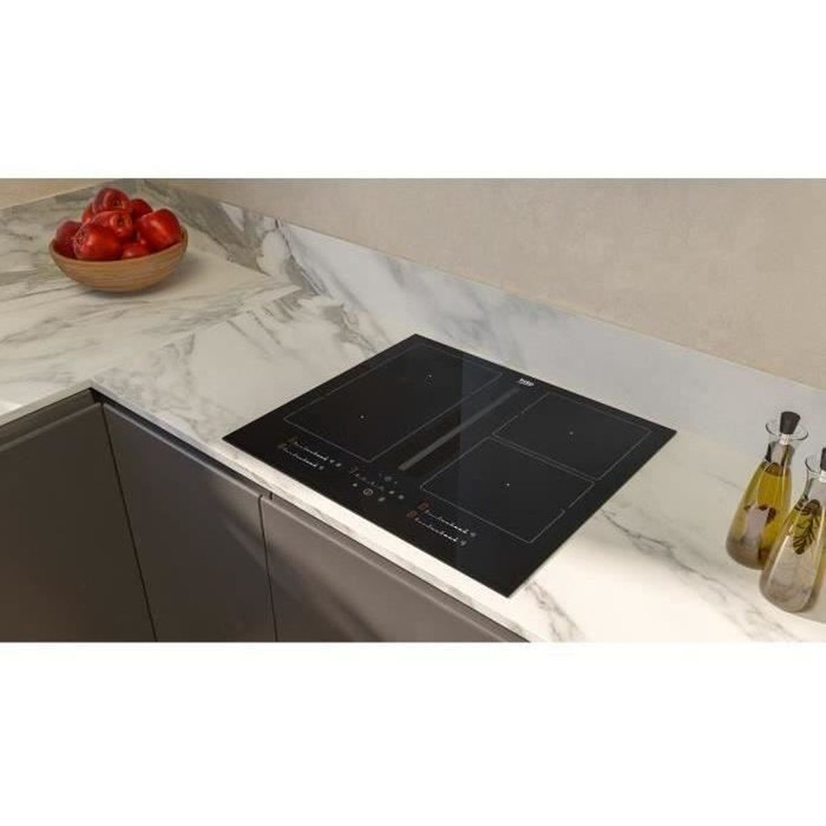 Un moderno piano cucina con piano cottura nero, pomodori in una ciotola di legno e bottiglie d'olio.