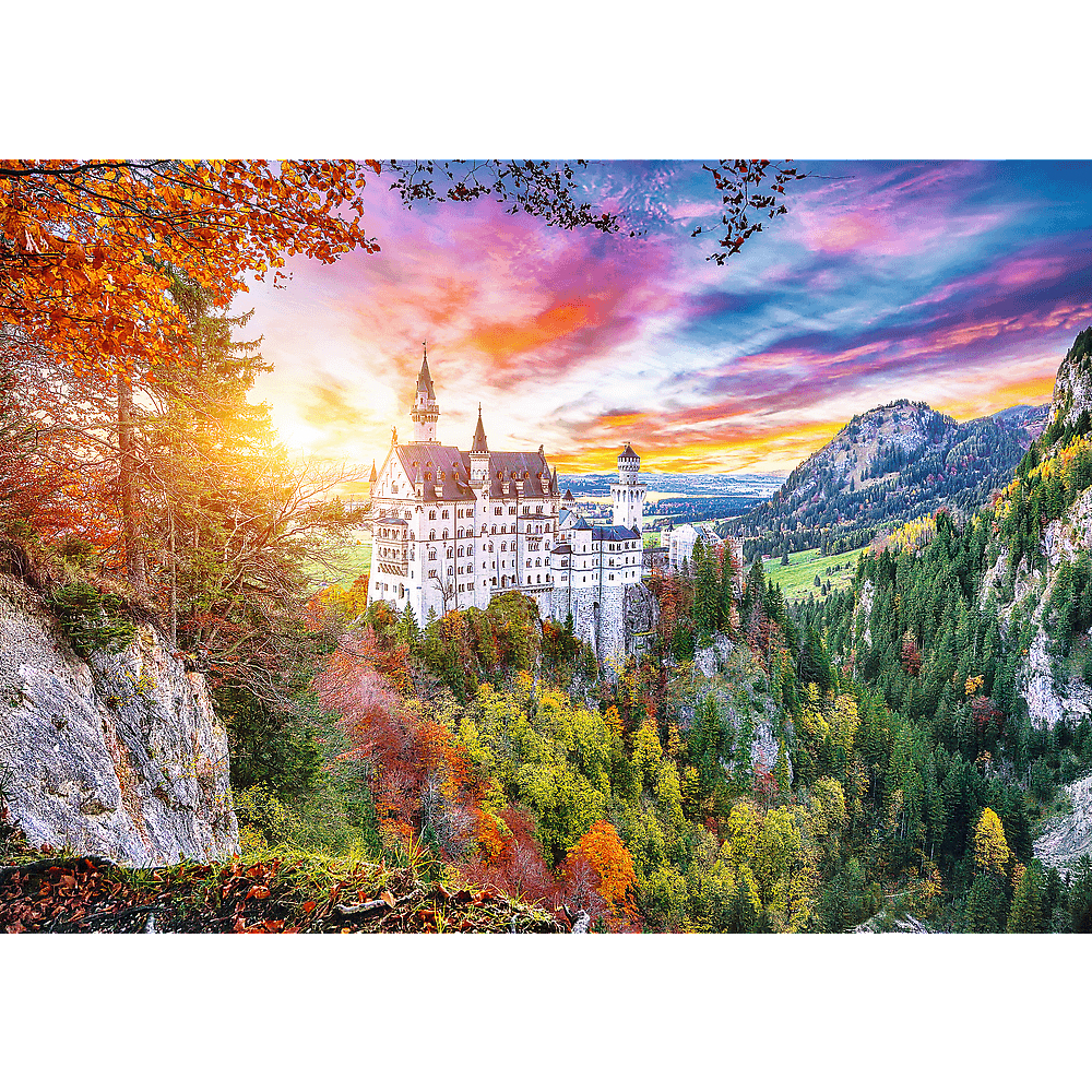 El castillo de Neuschwanstein está en una colina, rodeado de árboles otoñales coloridos y montañas, bajo un cielo de atardecer.