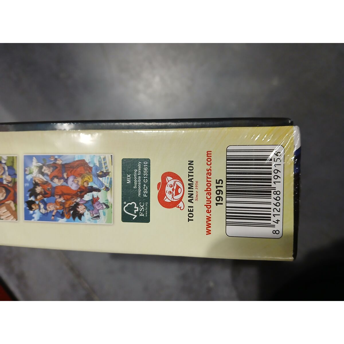 Seitenansicht der Box mit Cartoonfiguren, FSC-Logo, Toei Animation-Logo und Barcode. Die Box ist in Klarsichtfolie eingewickelt.