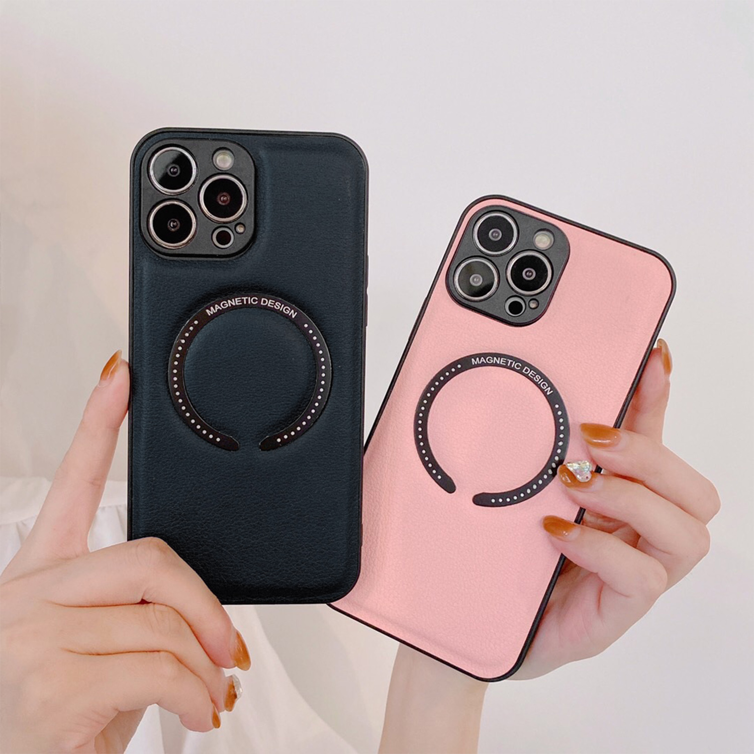 Zwei Handyhüllen, schwarz und rosa, mit Magnetdesignringen, gehalten von Händen. Die schwarze Hülle ist links, die rosa rechts.