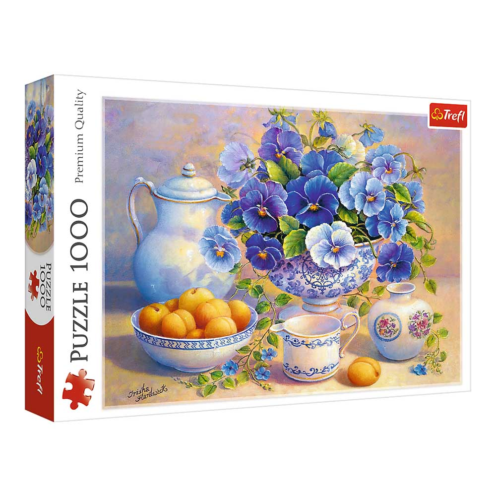 Pudełko z puzzlami z martwą naturą. Kwiaty w wazonie, owoce i czajniczek. Kolory niebieski, biały i żółty dominują.