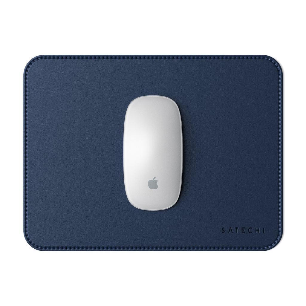 Un mouse Apple bianco è appoggiato su un tappetino blu navy con bordi cuciti. Il logo Satechi è visibile.