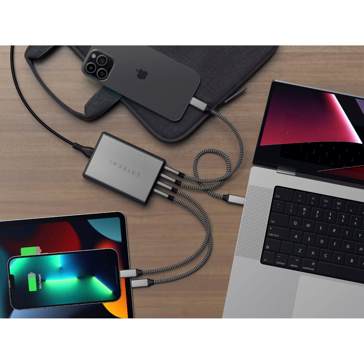 Un escritorio con una estación de carga y dispositivos. Incluye un teléfono, un iPad, una computadora portátil, todos conectados al cargador. 76% cargado en el teléfono.