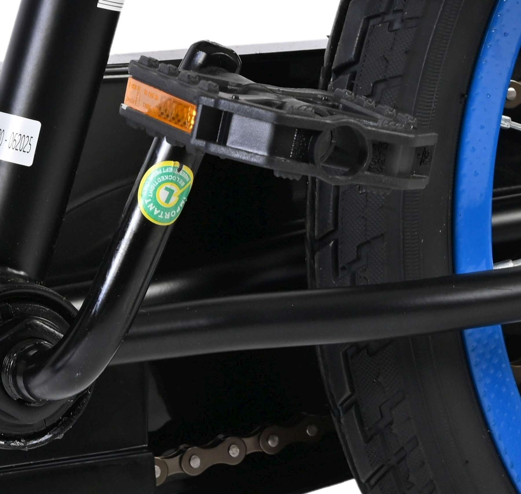 Nahaufnahme eines schwarzen Fahrradpedals mit bernsteinfarbenem Reflektor. Rechts ein schwarzer Reifen mit blauem Rand.