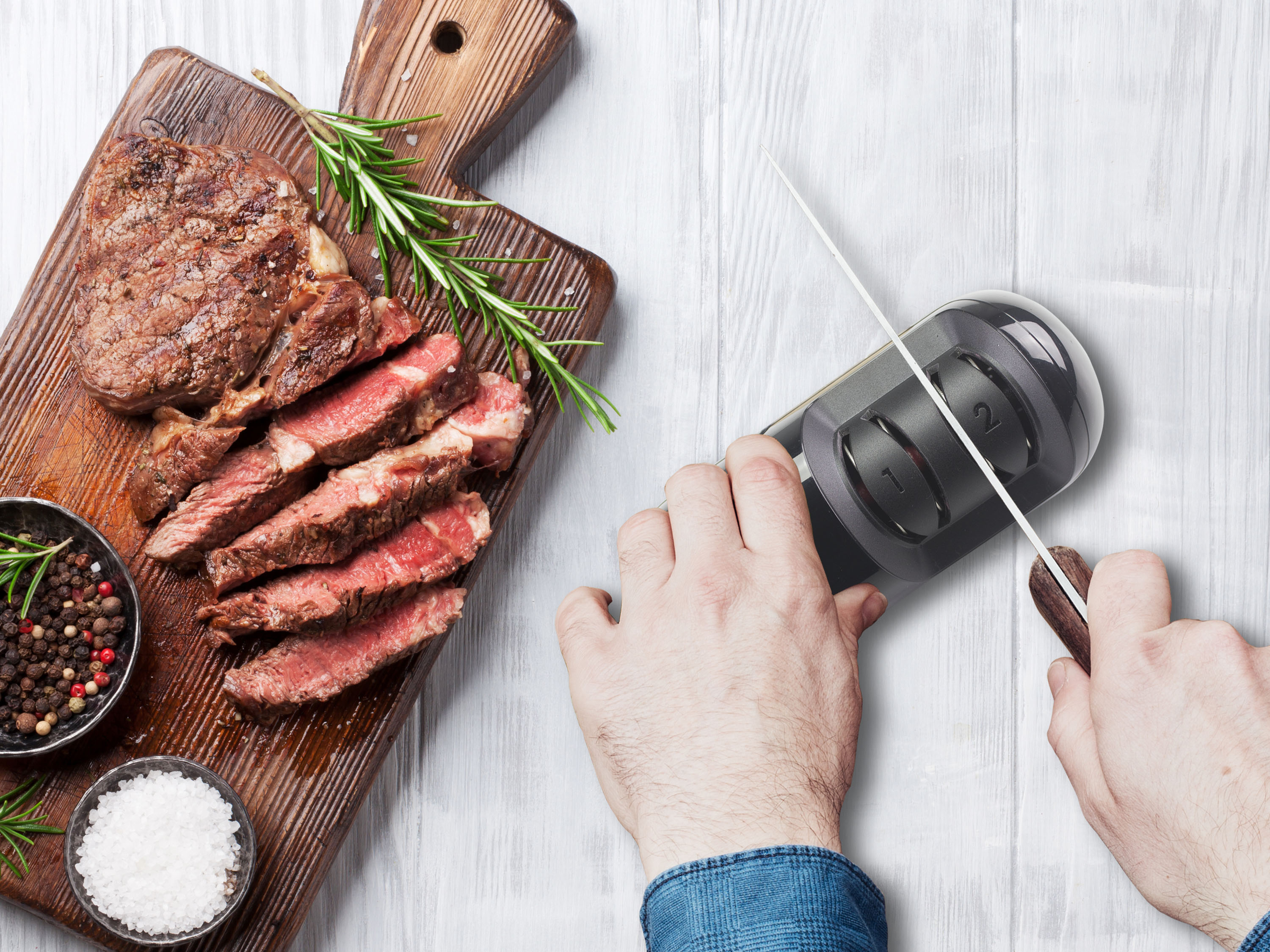 Bistecca a fette su tagliere con spezie. Si usa un affilacoltelli per affilare un coltello.