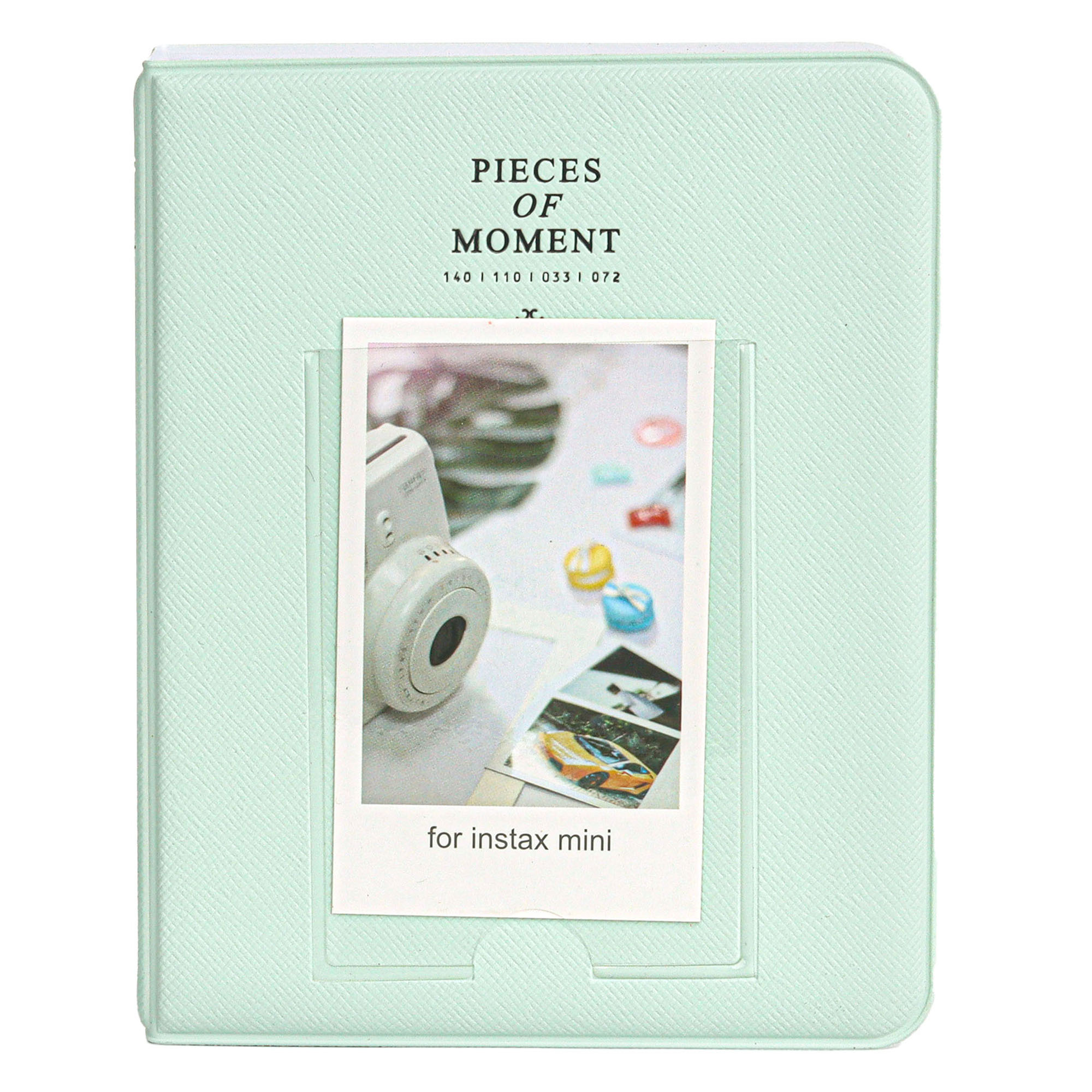 'PIECES OF MOMENT' yazılı, nane yeşili bir fotoğraf albümü, içinde bir anında fotoğraf makinesi ve fotoğraflar.