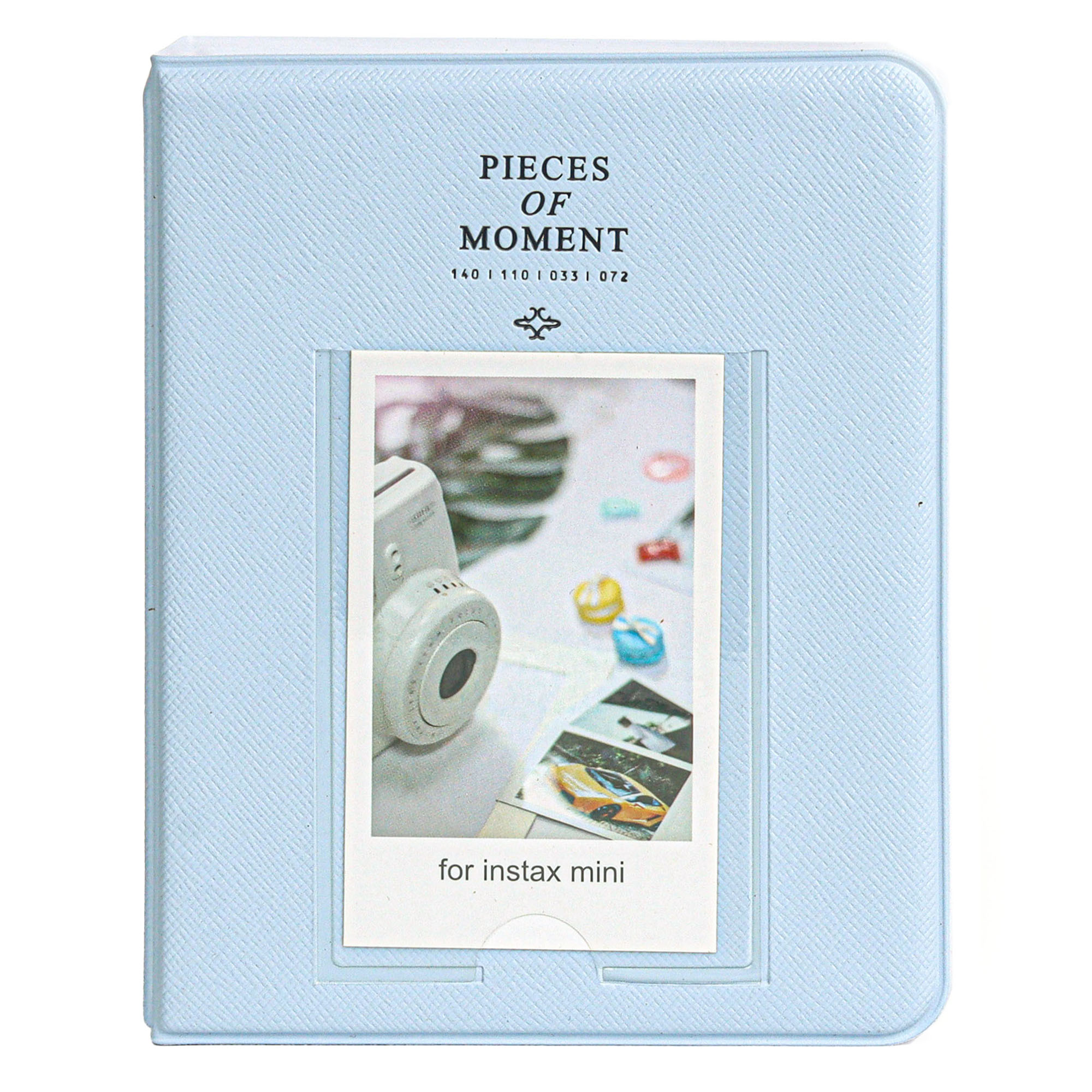 'PIECES OF MOMENT' yazılı açık mavi bir fotoğraf albümü. İçinde bir Instax Mini baskısı ve kamera var.